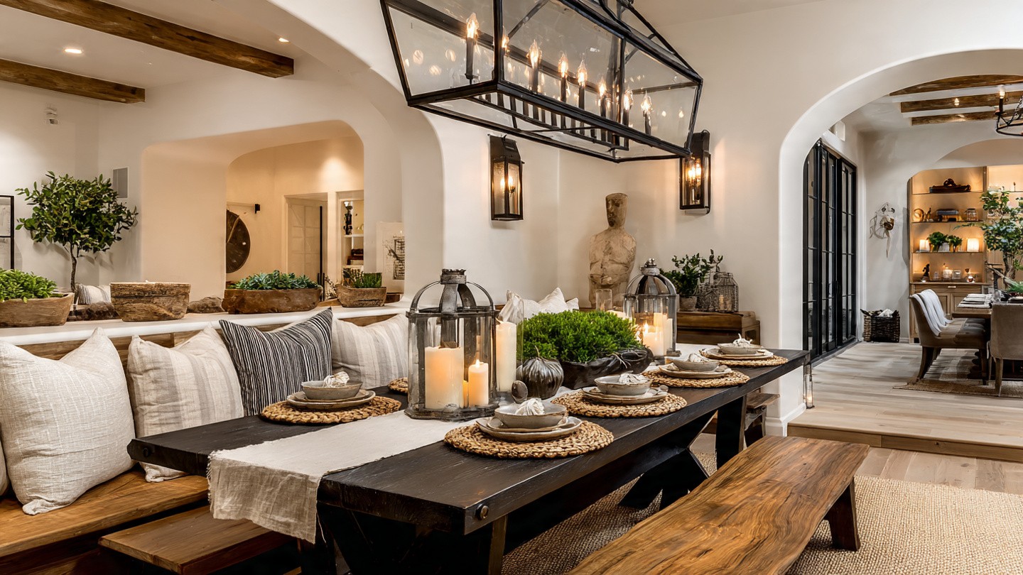 A cozy dining room with a rustic wooden table set for dinner. Candles in glass lanterns and greenery create a warm, inviting ambiance.