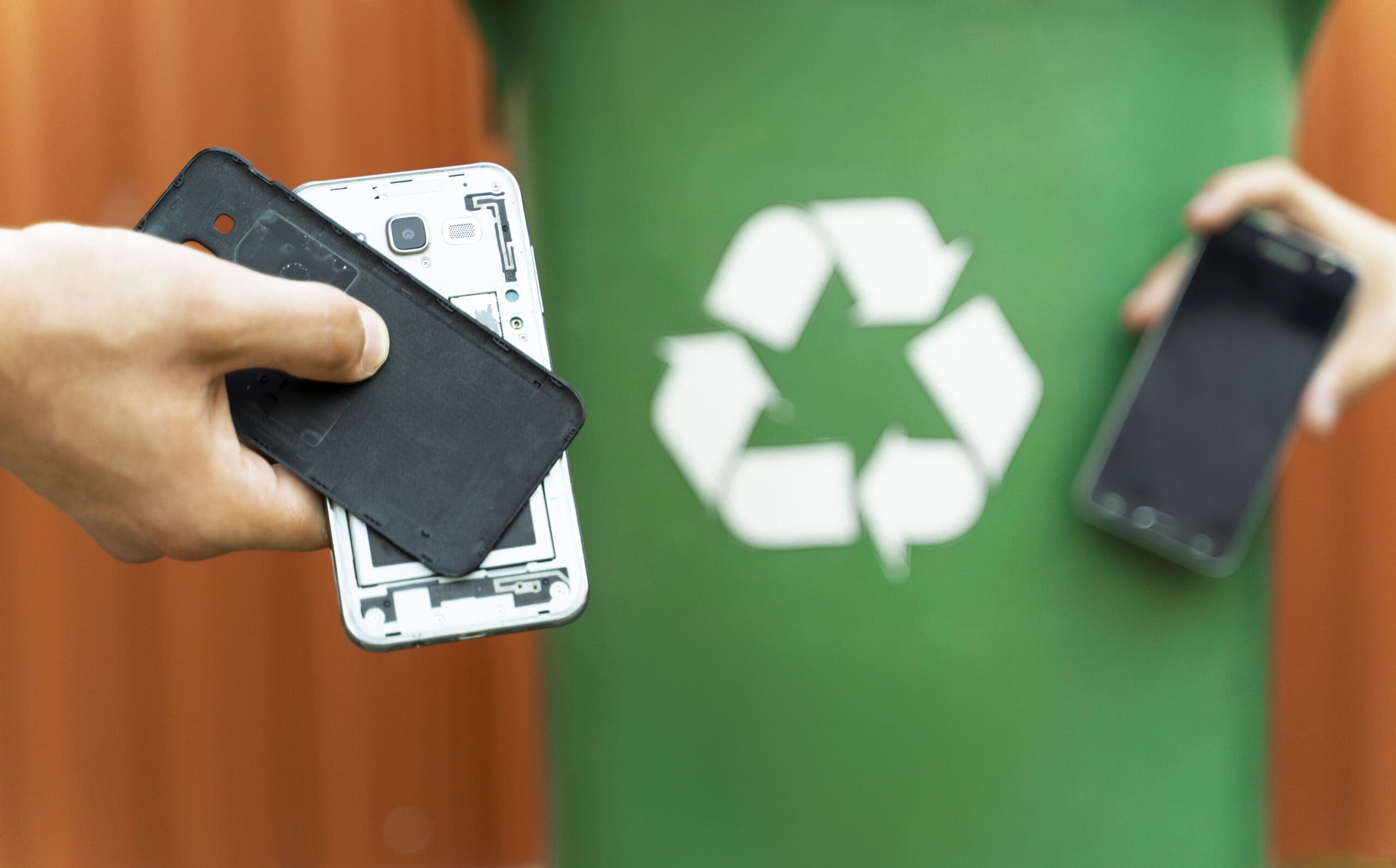 E waste, recycle concept, disassembled smartphone and recycle bin in background