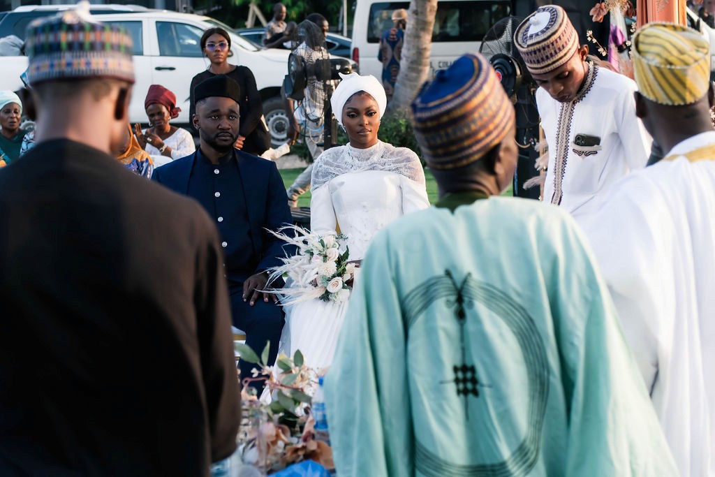 Luxury wedding planned by Victoria Brooks Events in Nigeria with elegant décor and beautiful reception. Groom in a blue suit and bride in a white wedding dress with flowers surrounded by family and friends.