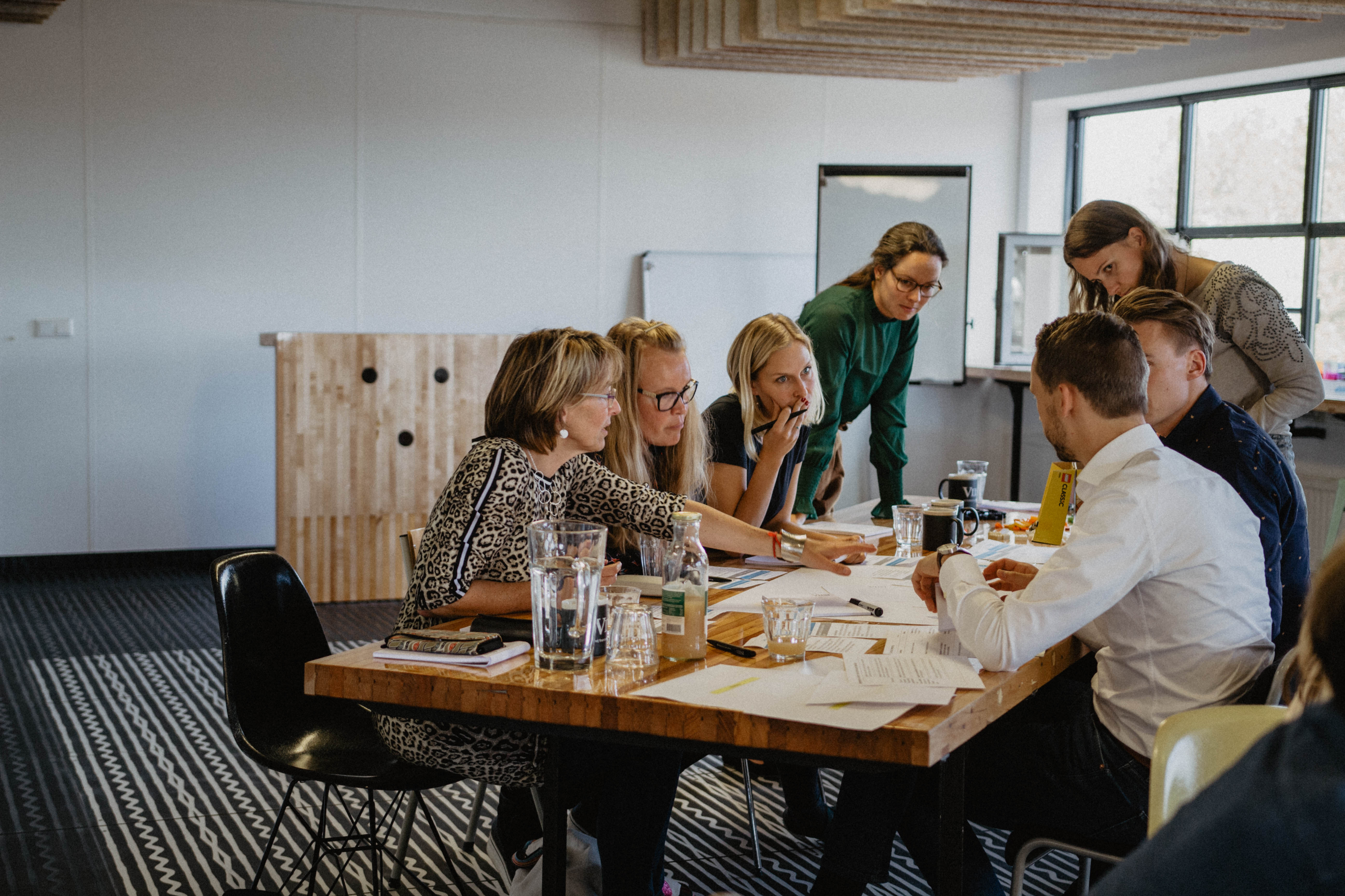 Team members collaborating in a meeting room around a shared table