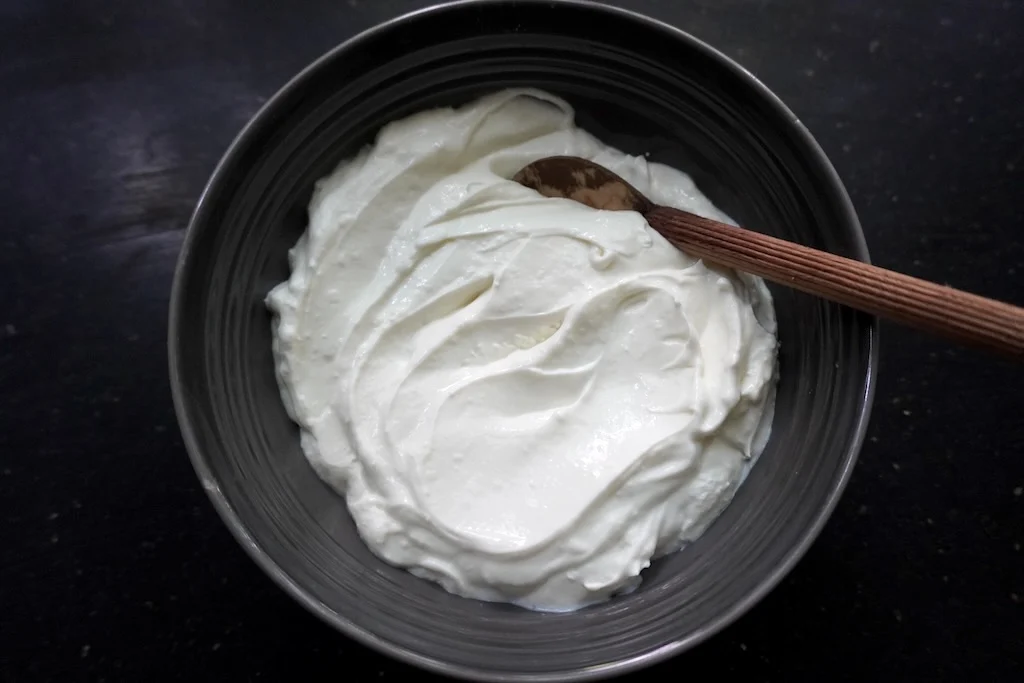 greek yogurt in a bowl with a wooden spoon