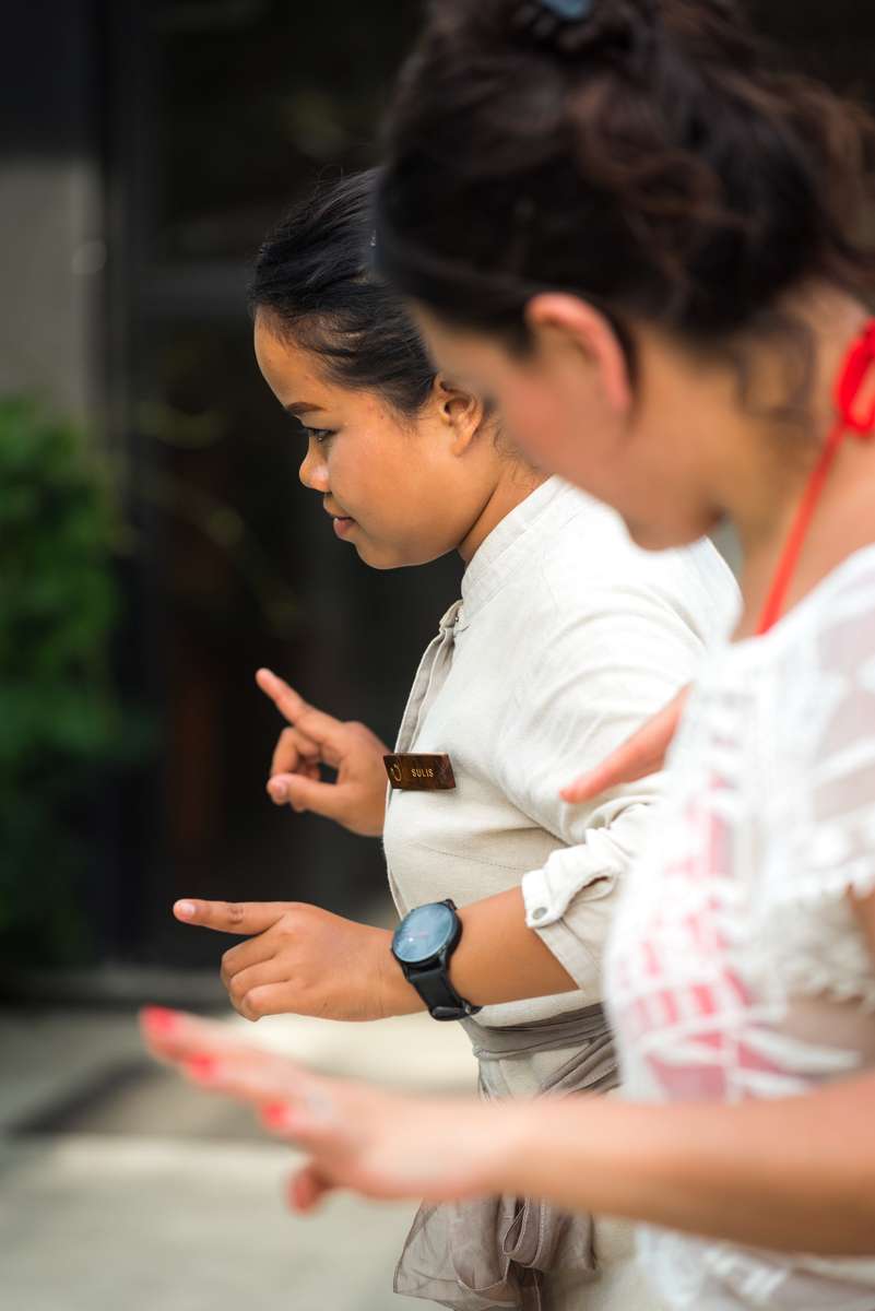 A young boy in a white shirt and a woman in a white patterned top interact while looking at something off-camera.