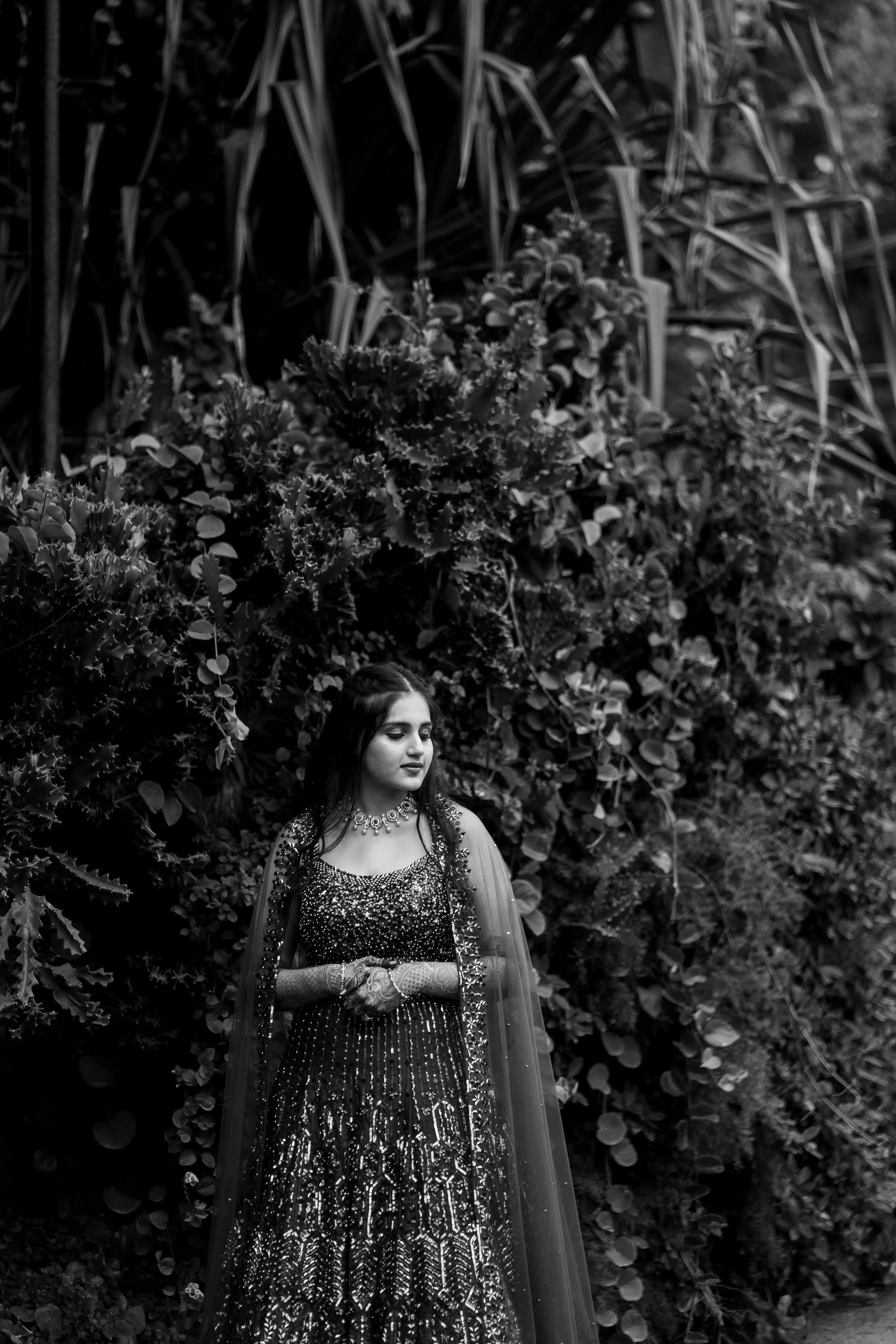 Tanya elegantly gazes away, surrounded by lush vines in a serene park. Black & white Fine Art Wedding Photography in Hyderabad by Out of The Blues.