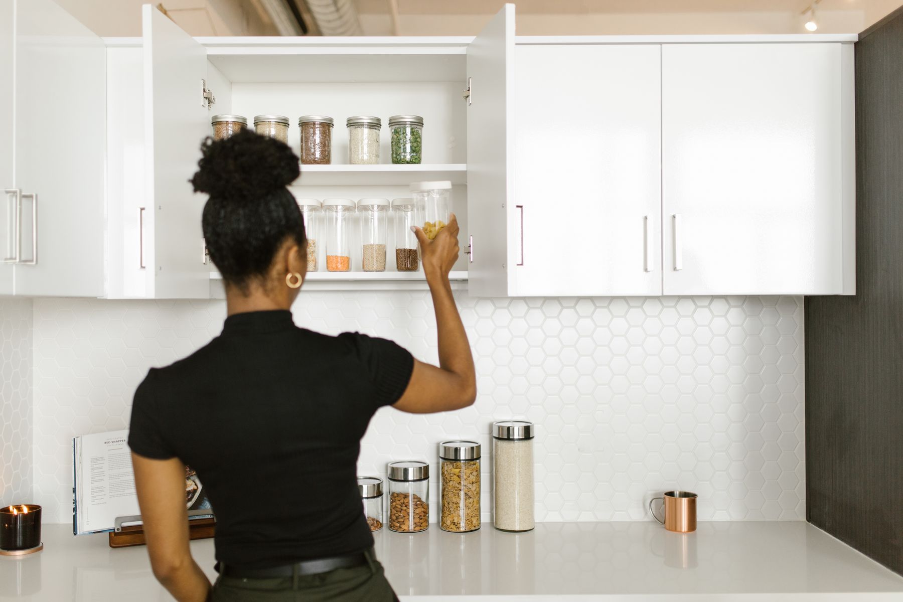Woman organizing food containers in a kitchen cabinet