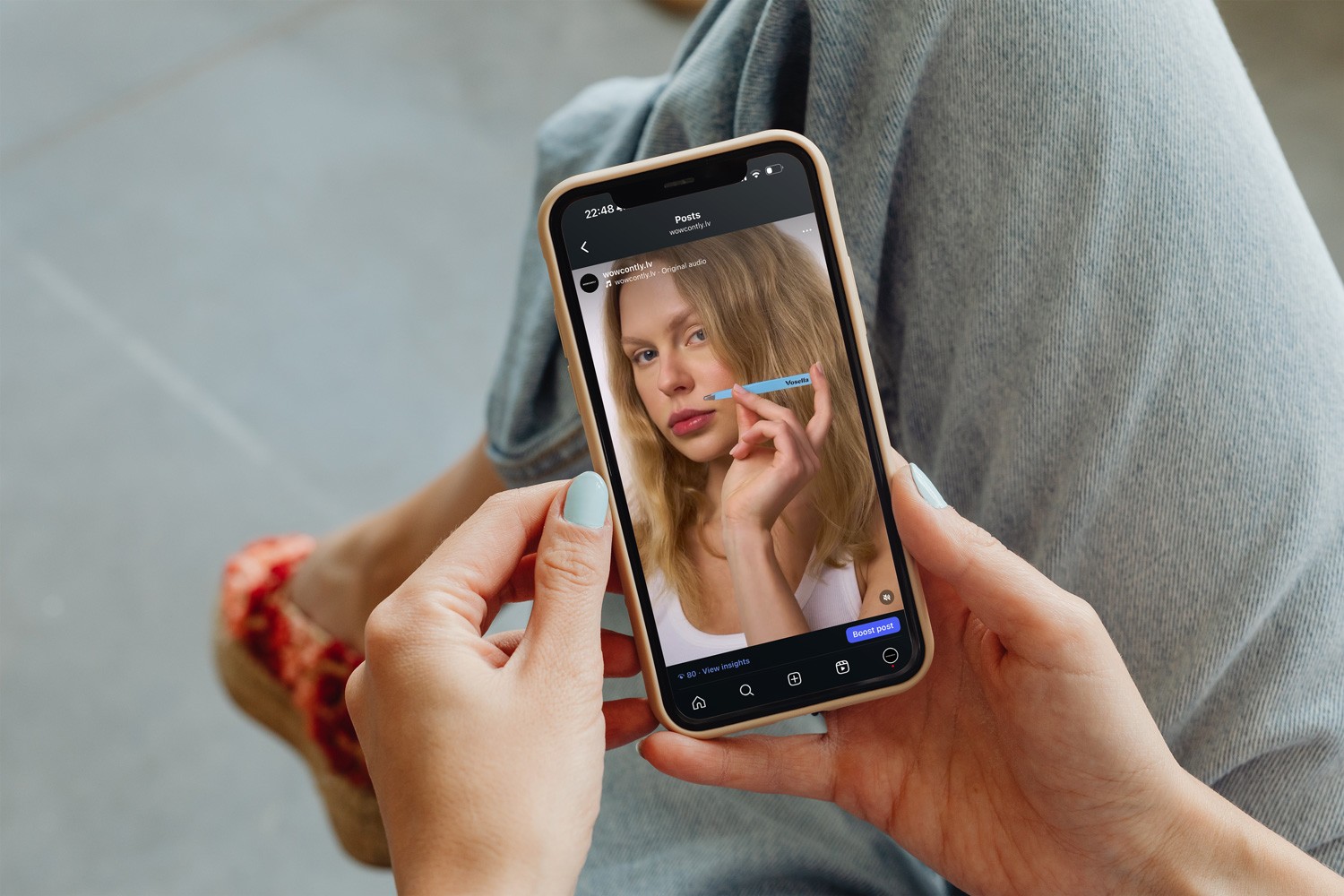 Женщина смотрит видео в Instagram о фотосессии косметической продукции — предметная съемка с моделью в Риге.