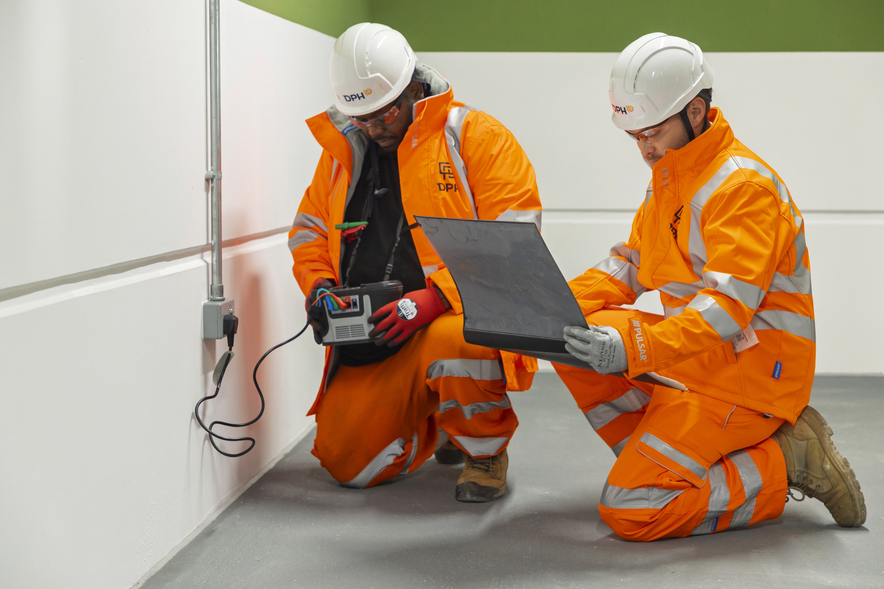 Modern glass building with illuminated facade and trees at sunset