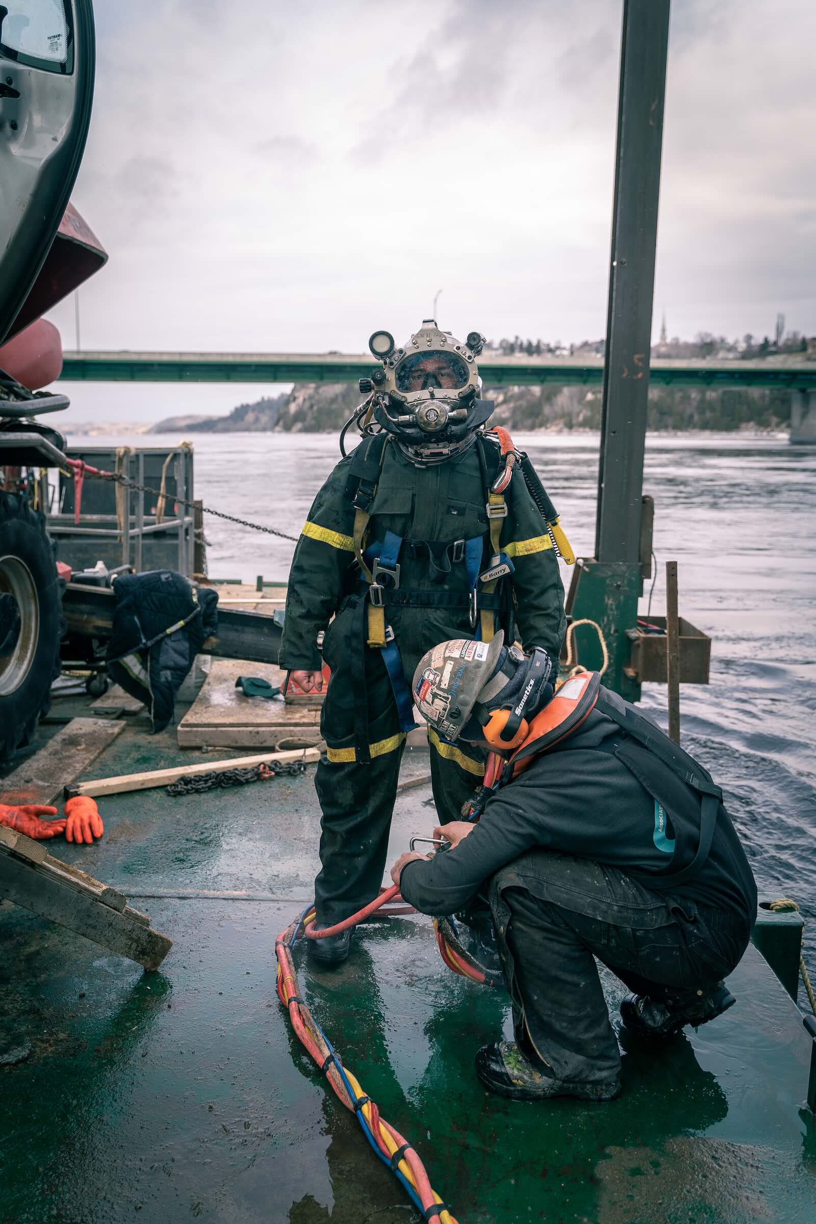 Deux plongeurs professionnels équipés sur un quai, préparant du matériel de plongée
