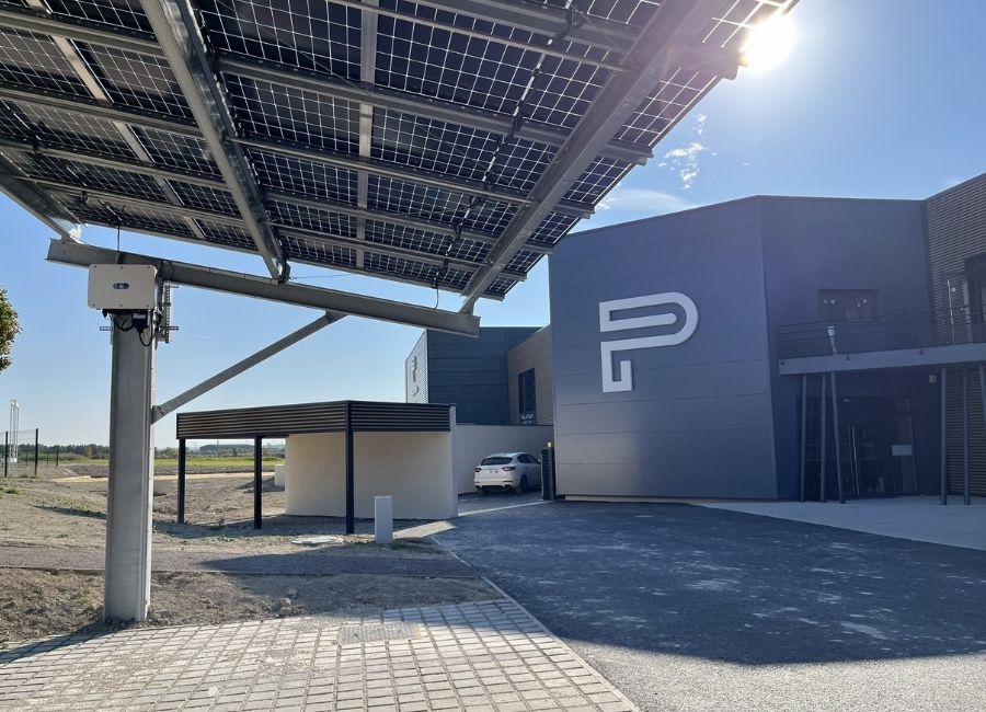 Entrée d’un bâtiment industriel moderne avec bardage gris et porte métallique.