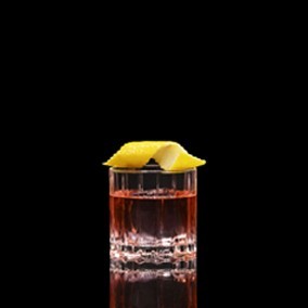 A closeup of a Sazerac drink against a dark background.