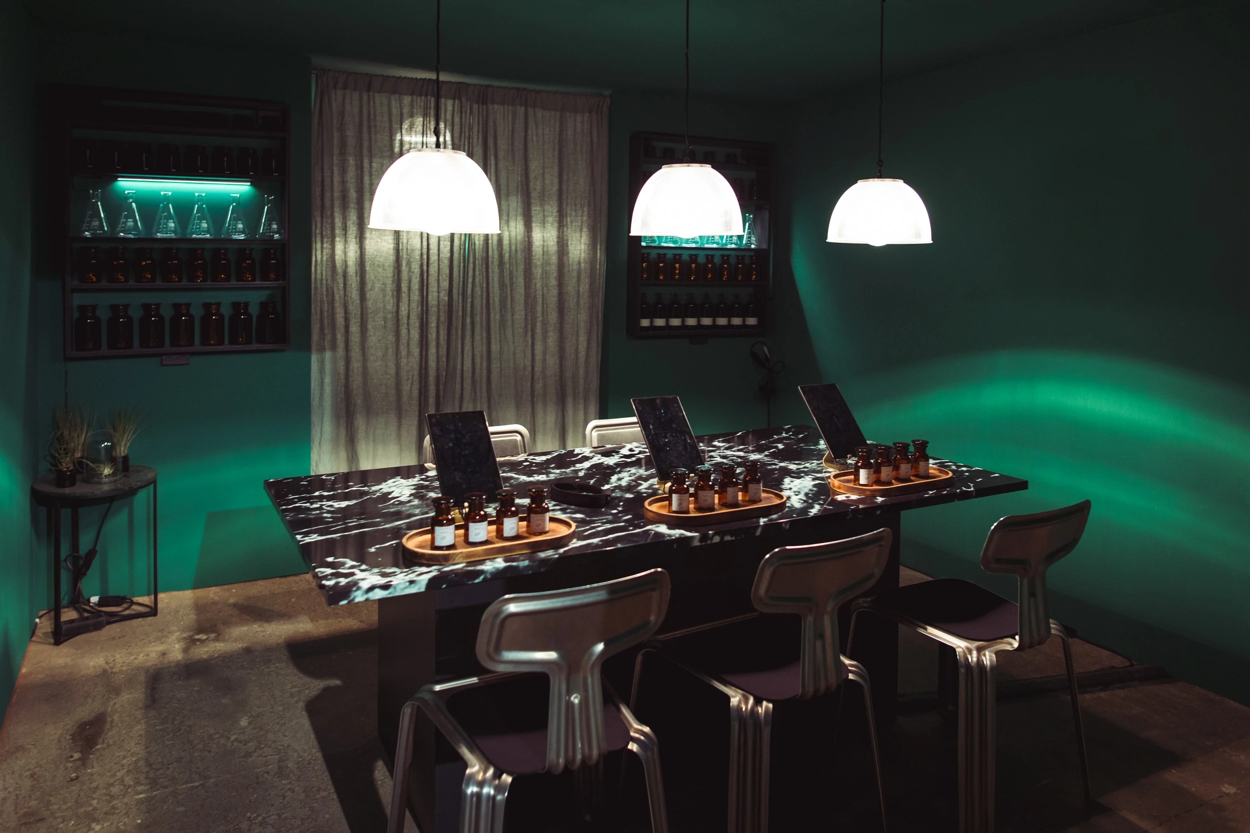 Green tasting room at DIAGEO BCB18 with a black marble table, tablets and tasting bottle sets, white dome lamps and backlit bottle niches.