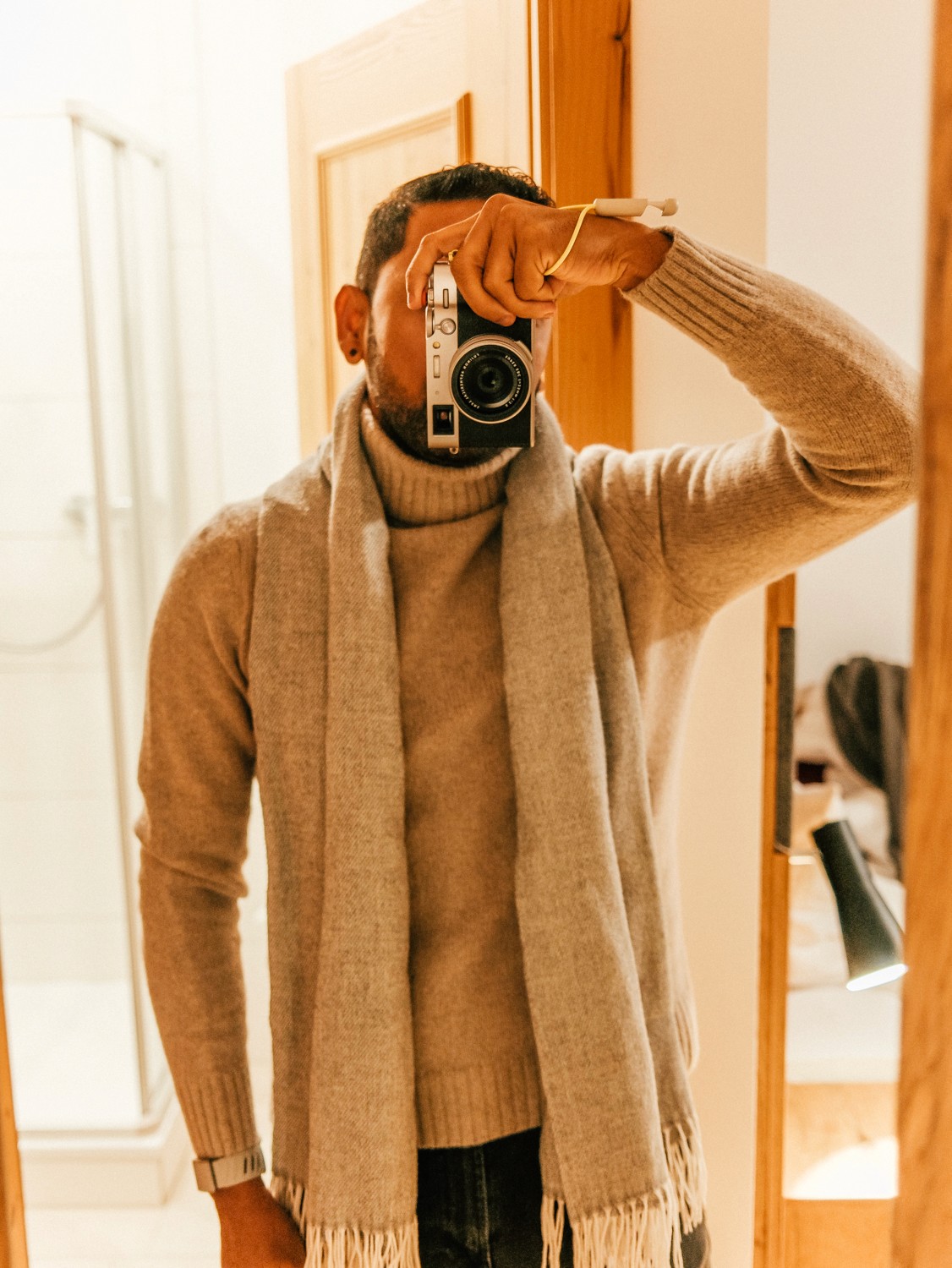 Smiling man with dreadlocks and glasses standing in a forest.