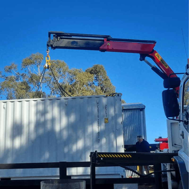 Crane truck lifting large container on site in Victoria, operated by Iron & Crane — safe lifting and precision placement services.