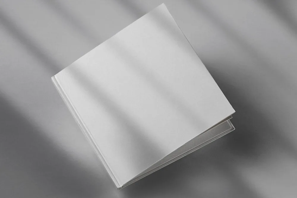 Square hardcover book mockup with bold beige typography on a vibrant coral cover. The book is displayed on a deep mauve background, with soft shadows creating a stylish and modern presentation.