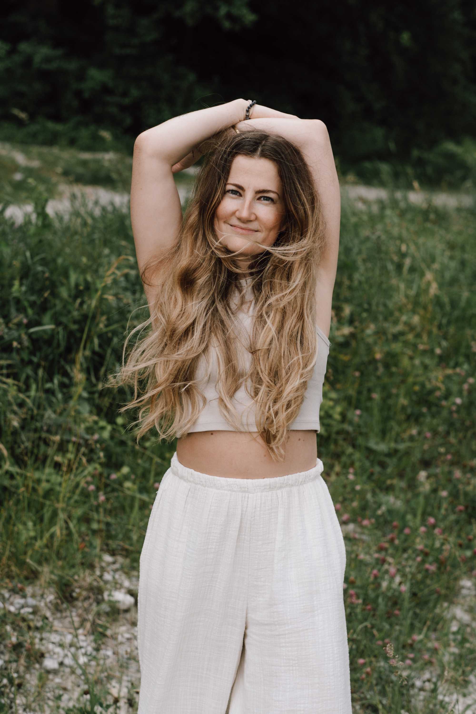 Antonia lächelnd mit Armen über dem Kopf auf Wiese