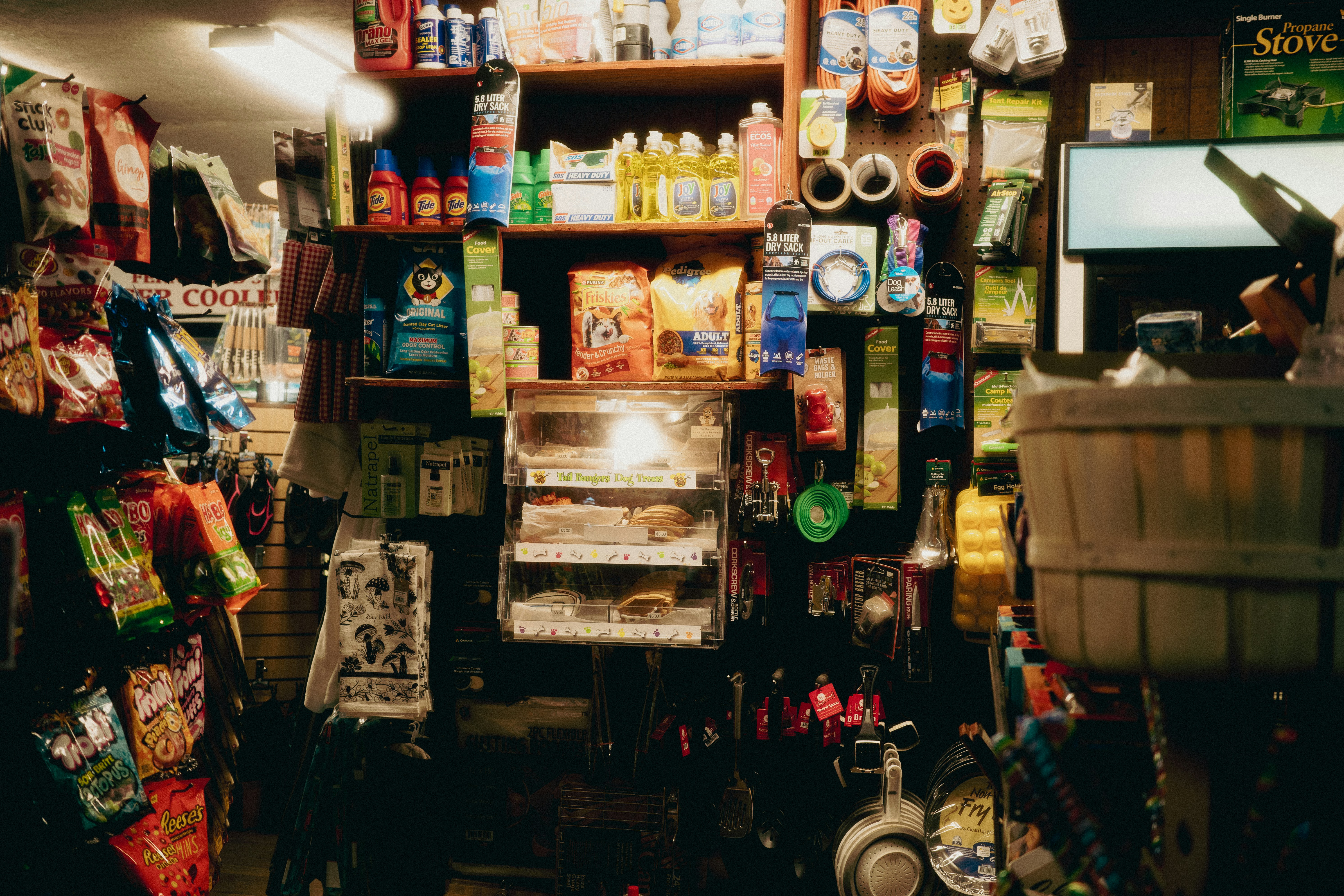 A cluttered convenience store aisle with shelves of goods.