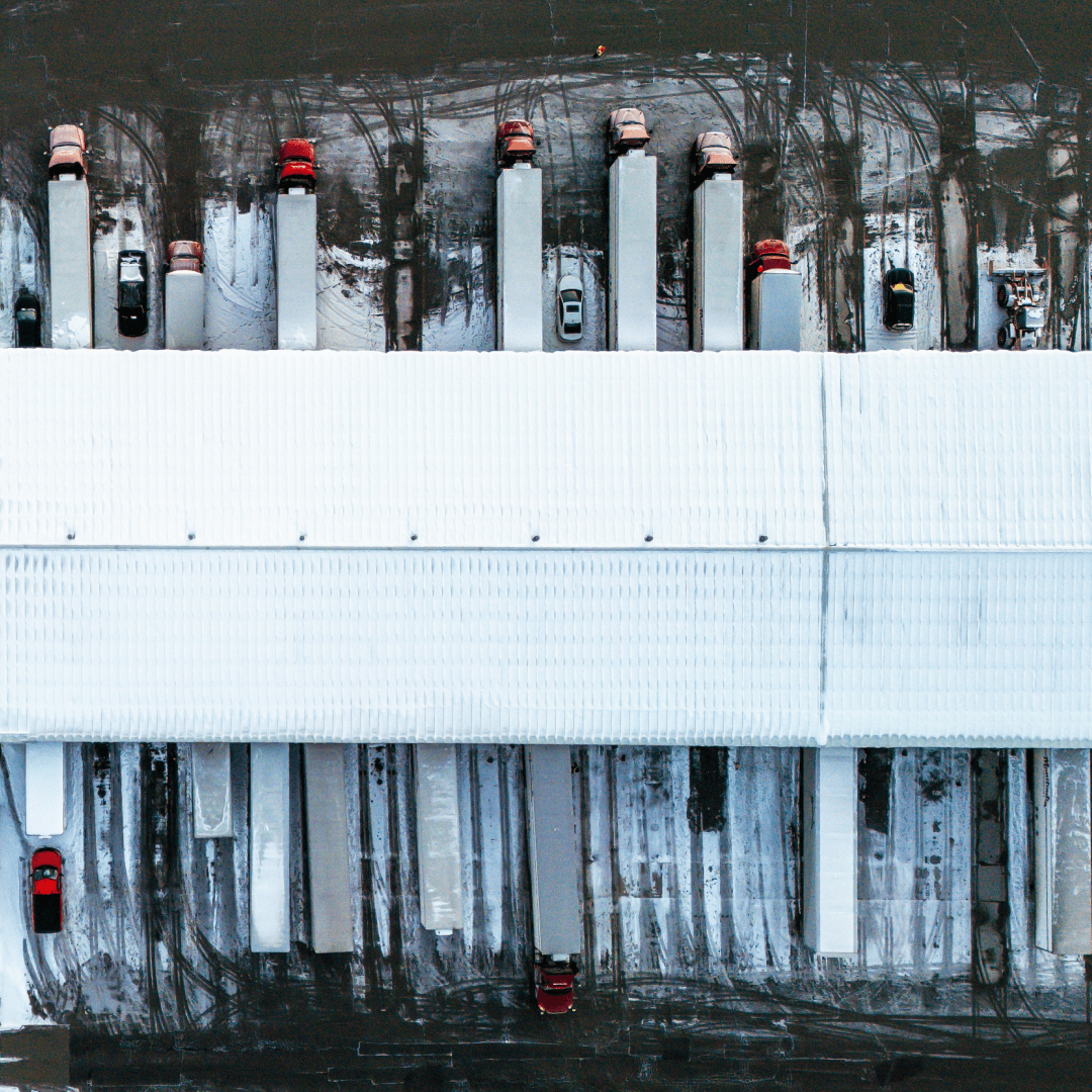 Overhead view of trucks at warehouse facility illustrating dock scheduling and digital driver check-in flow