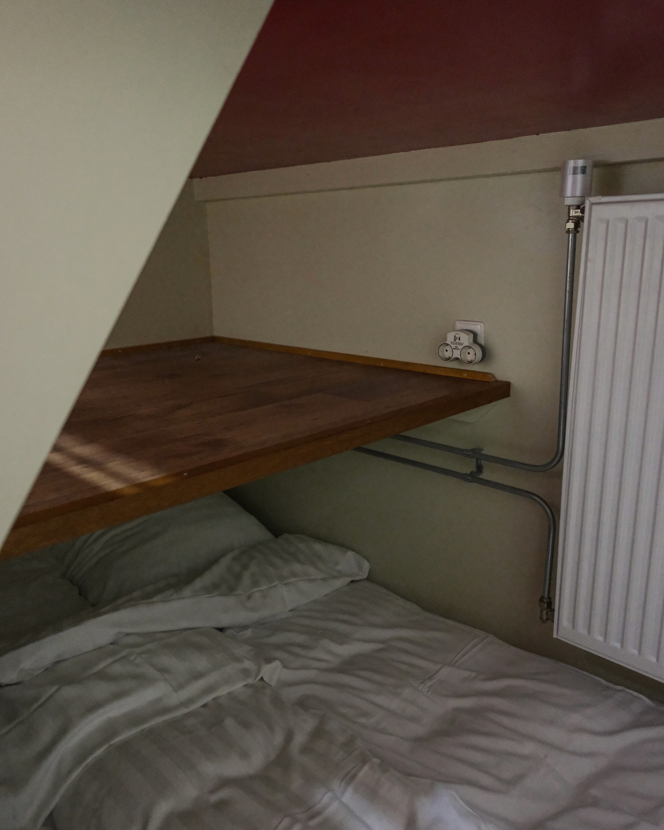 Beige upholstered bed with patterned pillows and ottomans