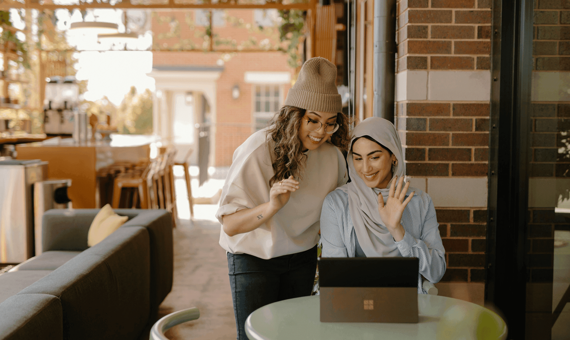 Two Women waving at laptop screen