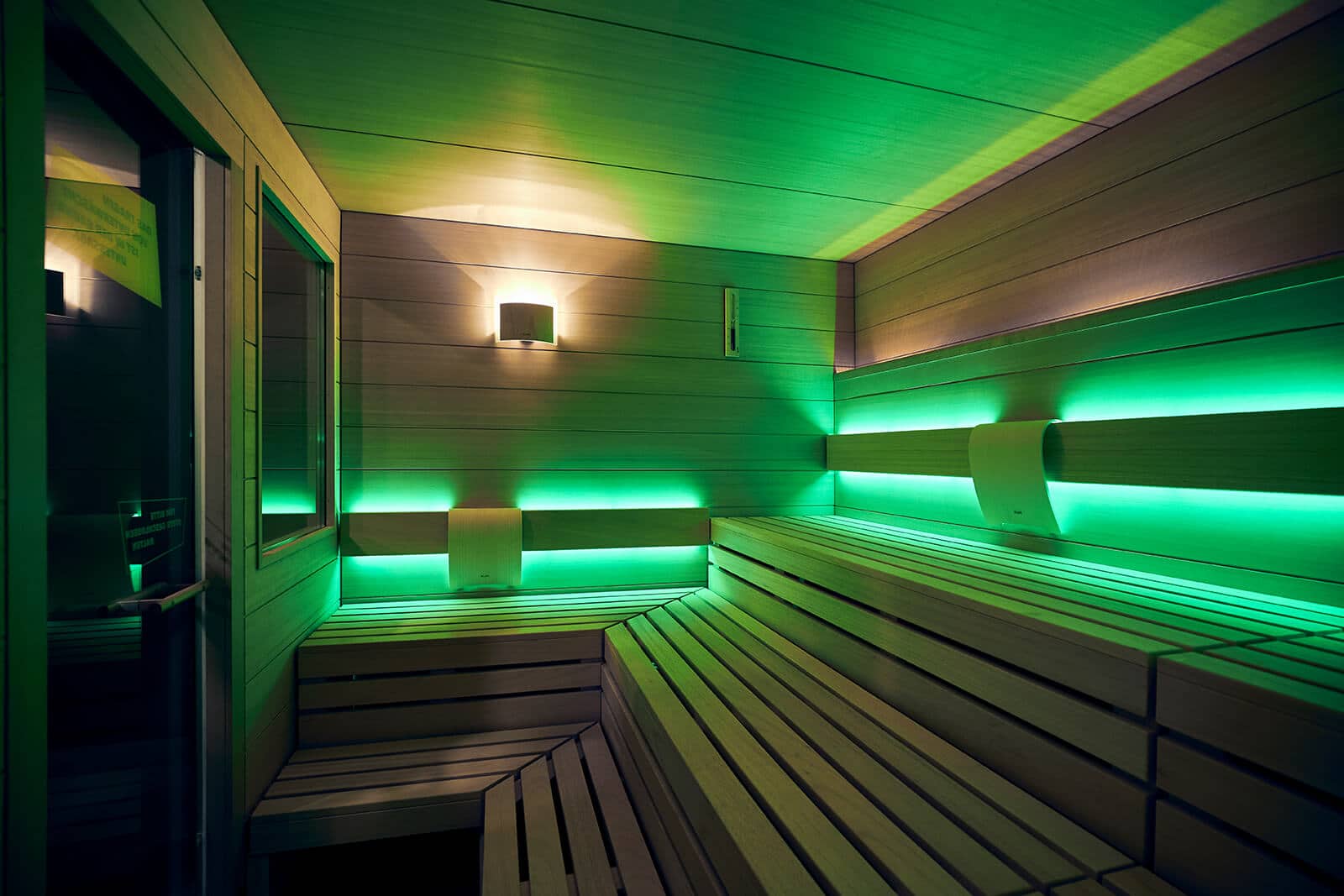  Sauna im XTRAFIT Fitnessstudio in Reutlingen mit grüner Beleuchtung und Holzinterieur.