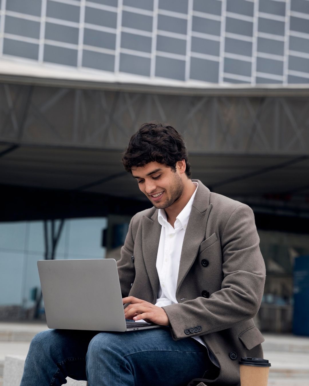 People seated around a table with laptops, 2 individuals engaged in work tasks.