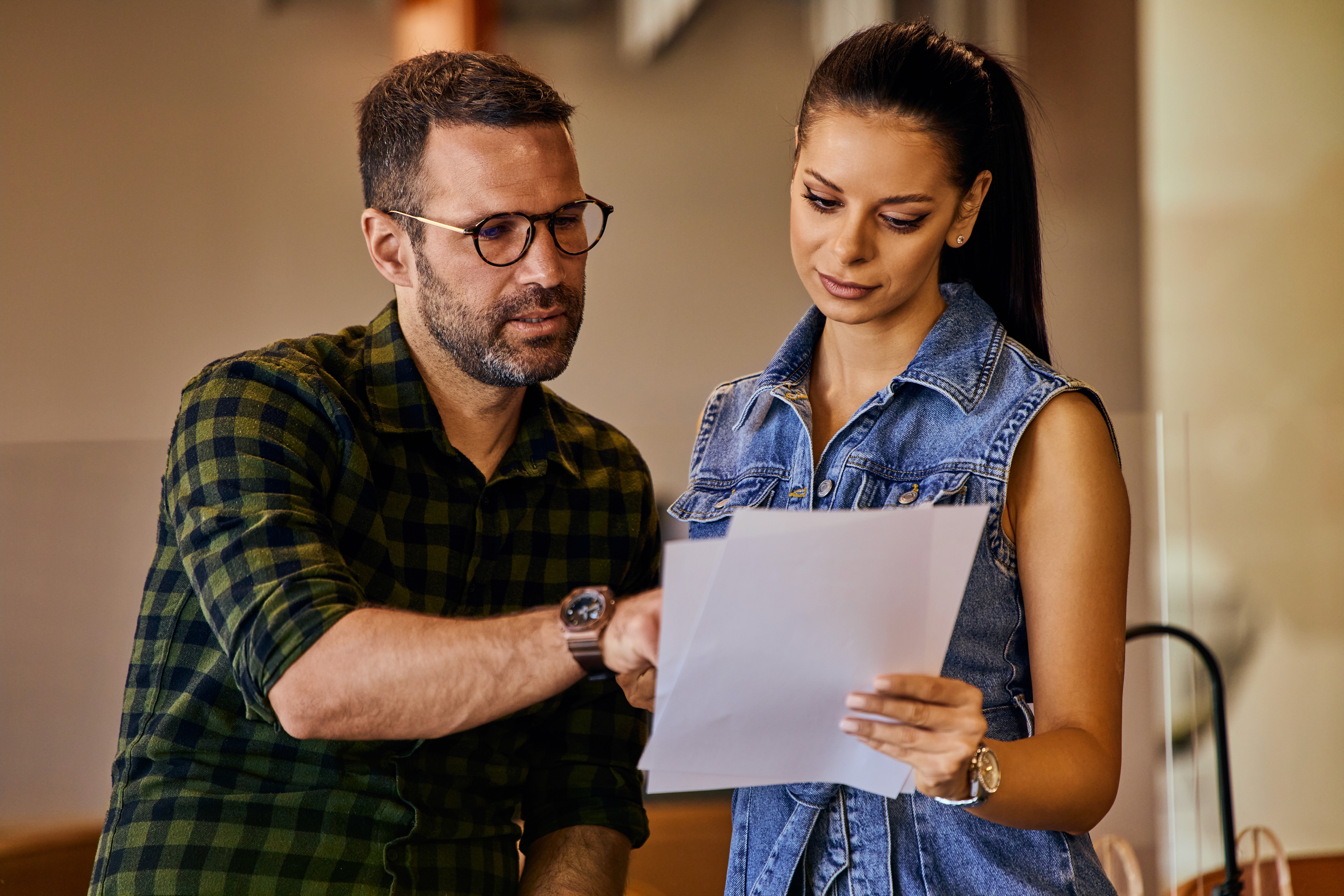 Paar sitzt zusammen am Tisch und prüft aufmerksam ein Dokument mit wichtigen Unterlagen.