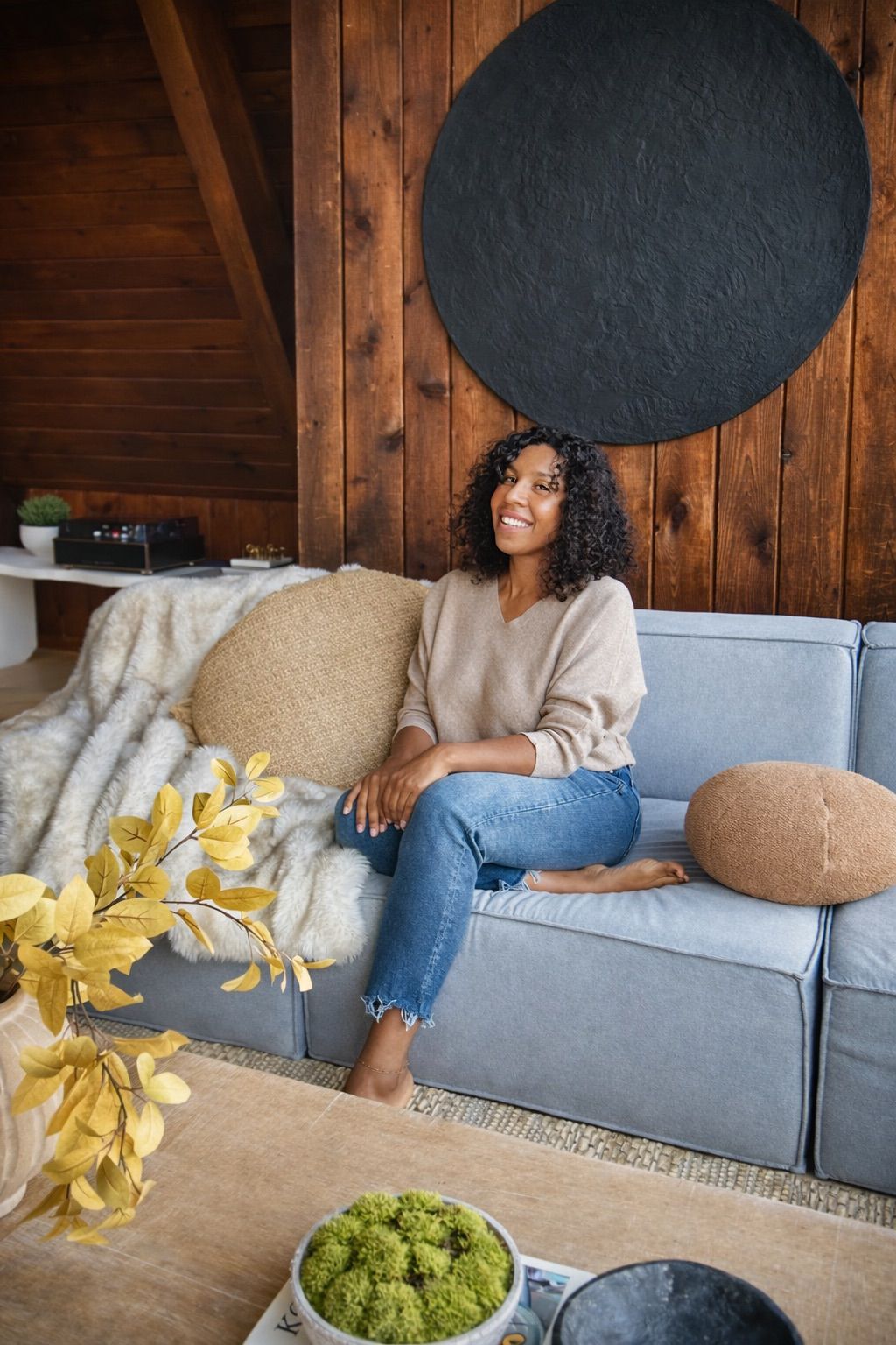 A smiling man with short hair stands with arms crossed, wearing a dark shirt against a neutral background.