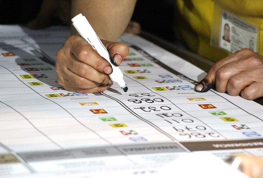 A hand holding a marker writing on a large sheet of paper