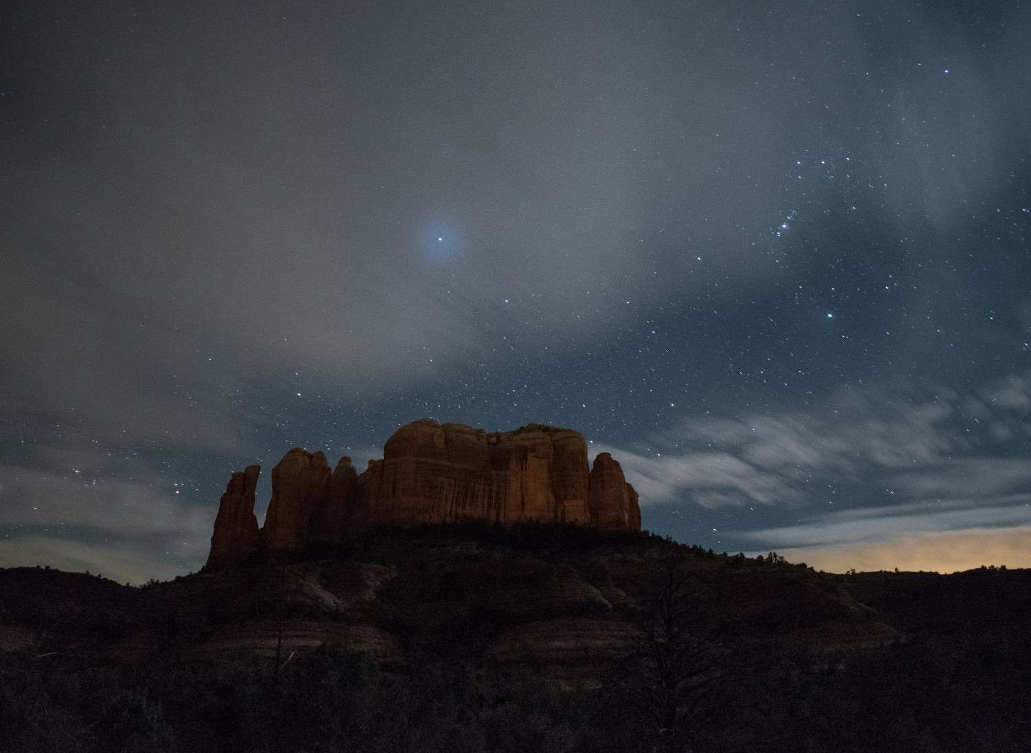 Night sky above desert rock formations with stars visible in the background