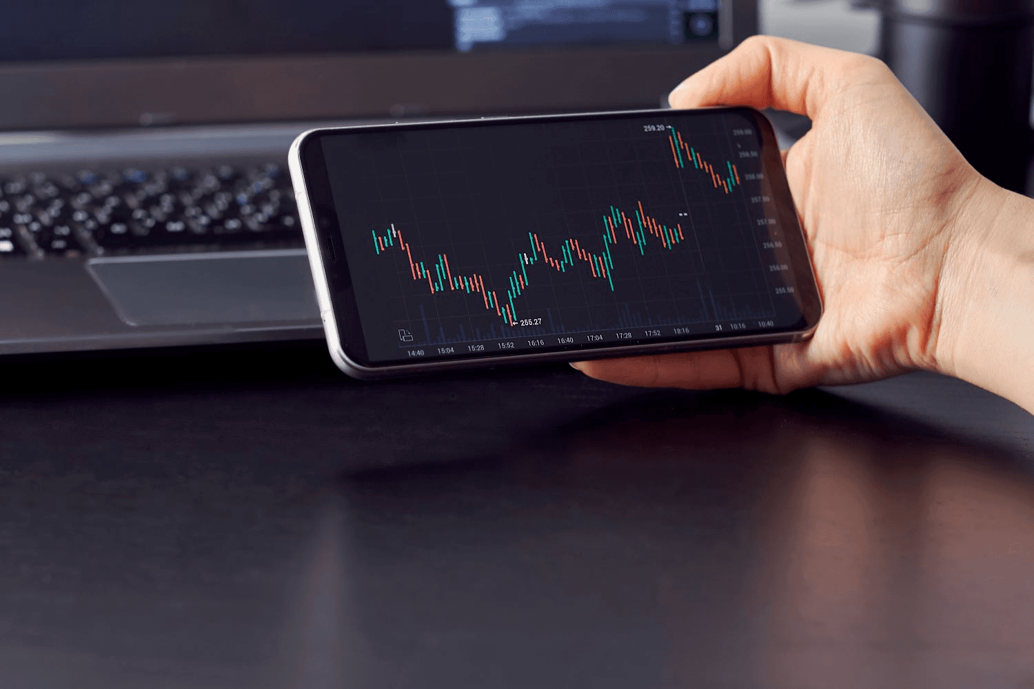 Person holding phone showing stock candlestick chart - How to Deposit on Polymarket 