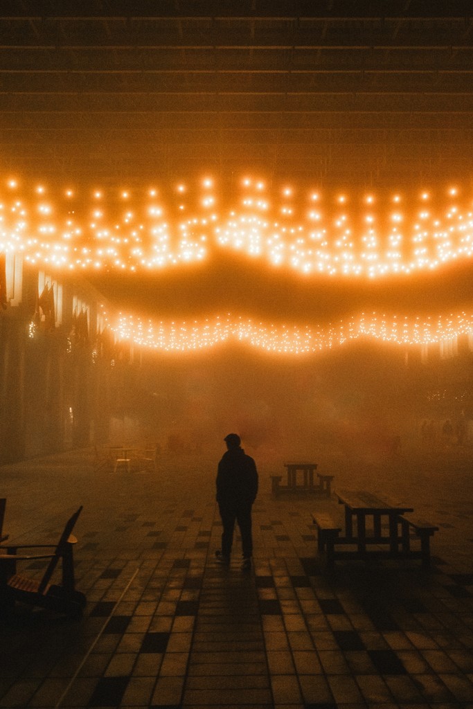 A man standing in a room with lights hanging from the ceiling