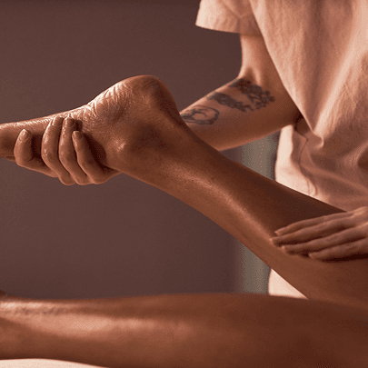 Une femme masse la jambe d'une personne