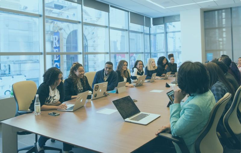 An inclusive group of professionals engaged in a collaborative business discussion around a large conference table, symbolizing teamwork and diverse perspectives in compensation strategy.