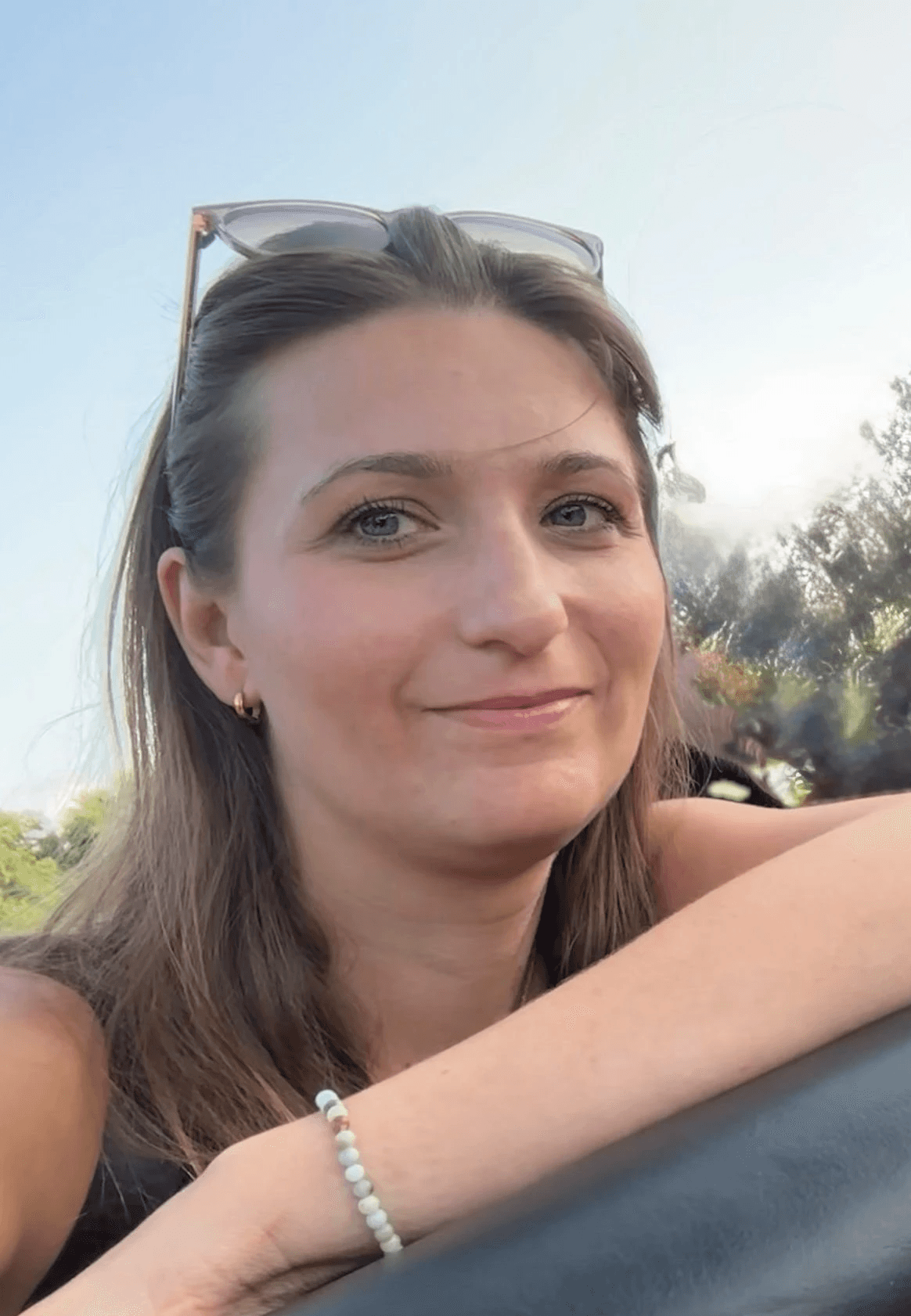 A person with shoulder-length blonde hair wearing a black newsboy cap and a black sweater.