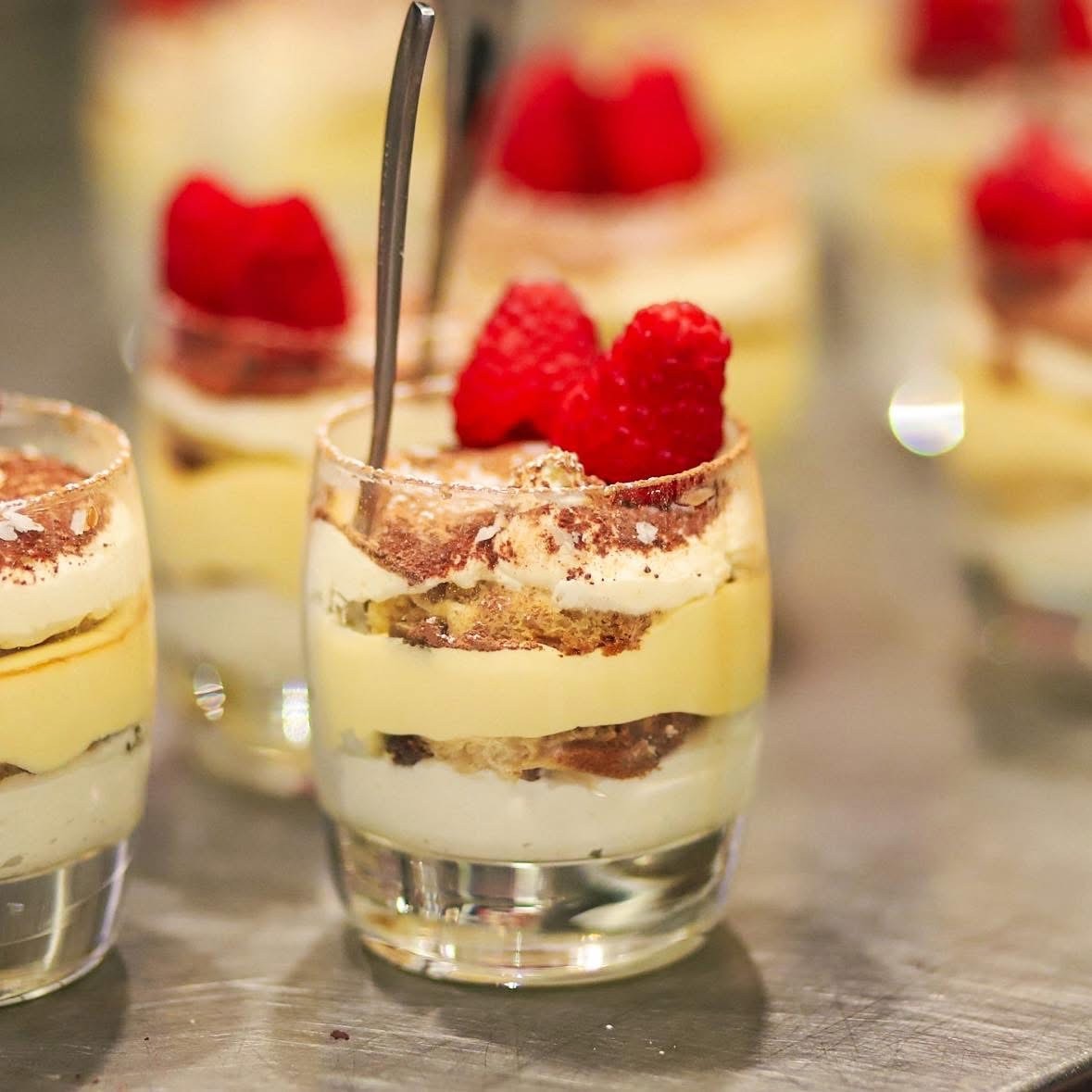 Miniature tiramisu dessert cups topped with fresh raspberries