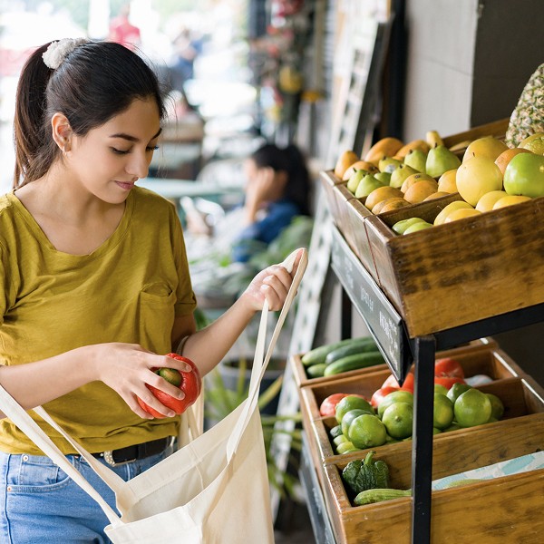 image of woman filling herreusable tote bag made from recycled material with vegetables