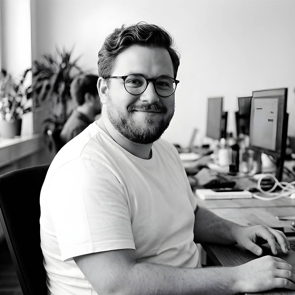 Portrait of a woman with long, smooth hair swept to the side, in a dark t-shirt, on a plain background.