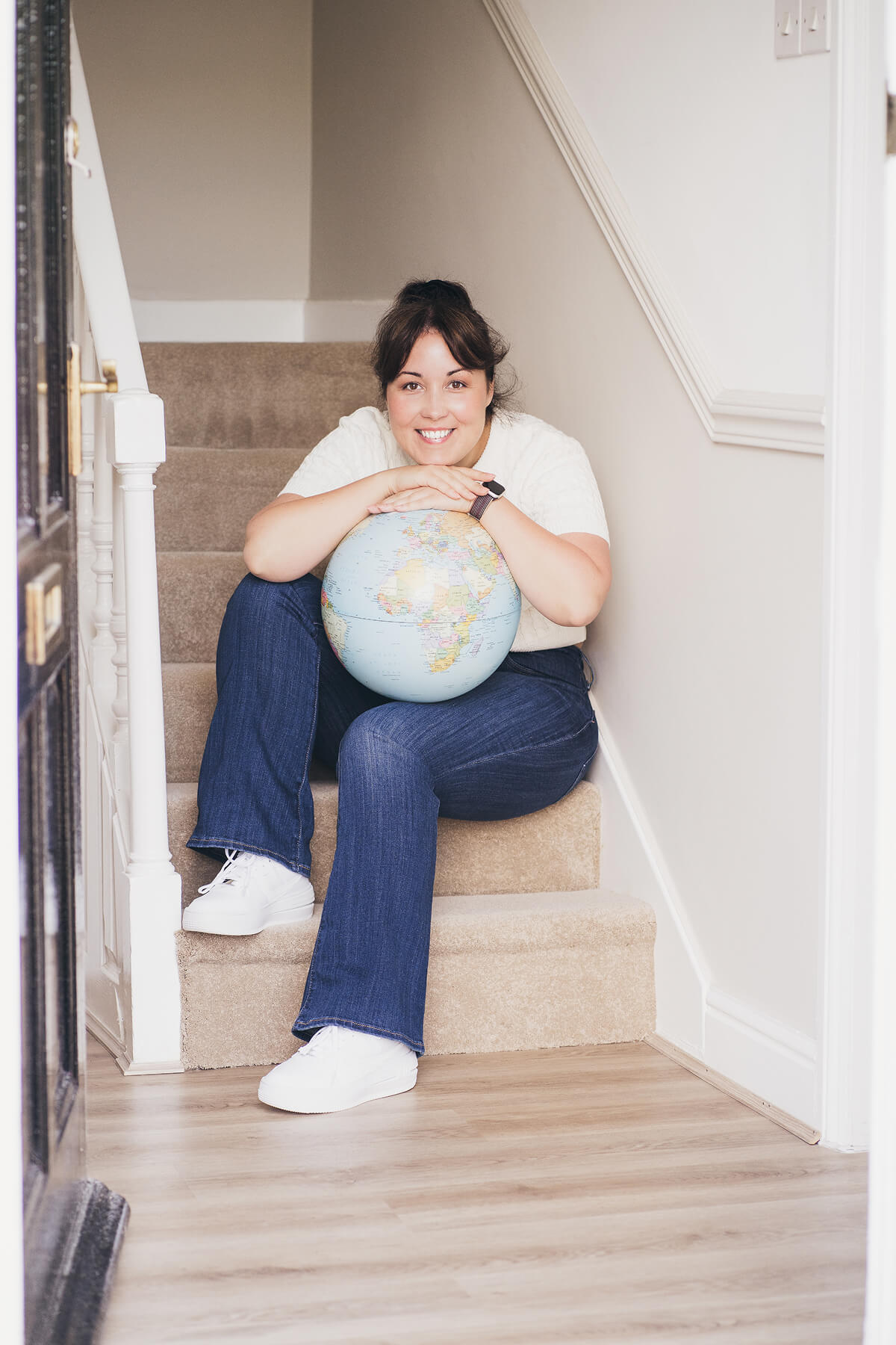Aniko Rucz, short-term rental host and mentor, sitting with a globe reflecting her international experience in hospitality
