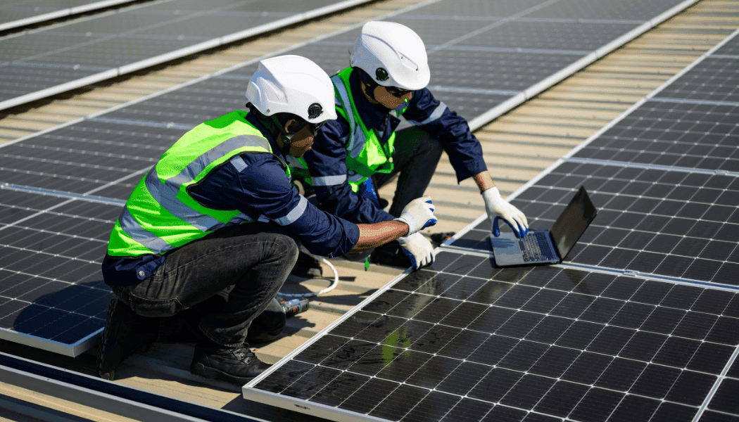Two engineers on rooftop solar installation witha a laptop