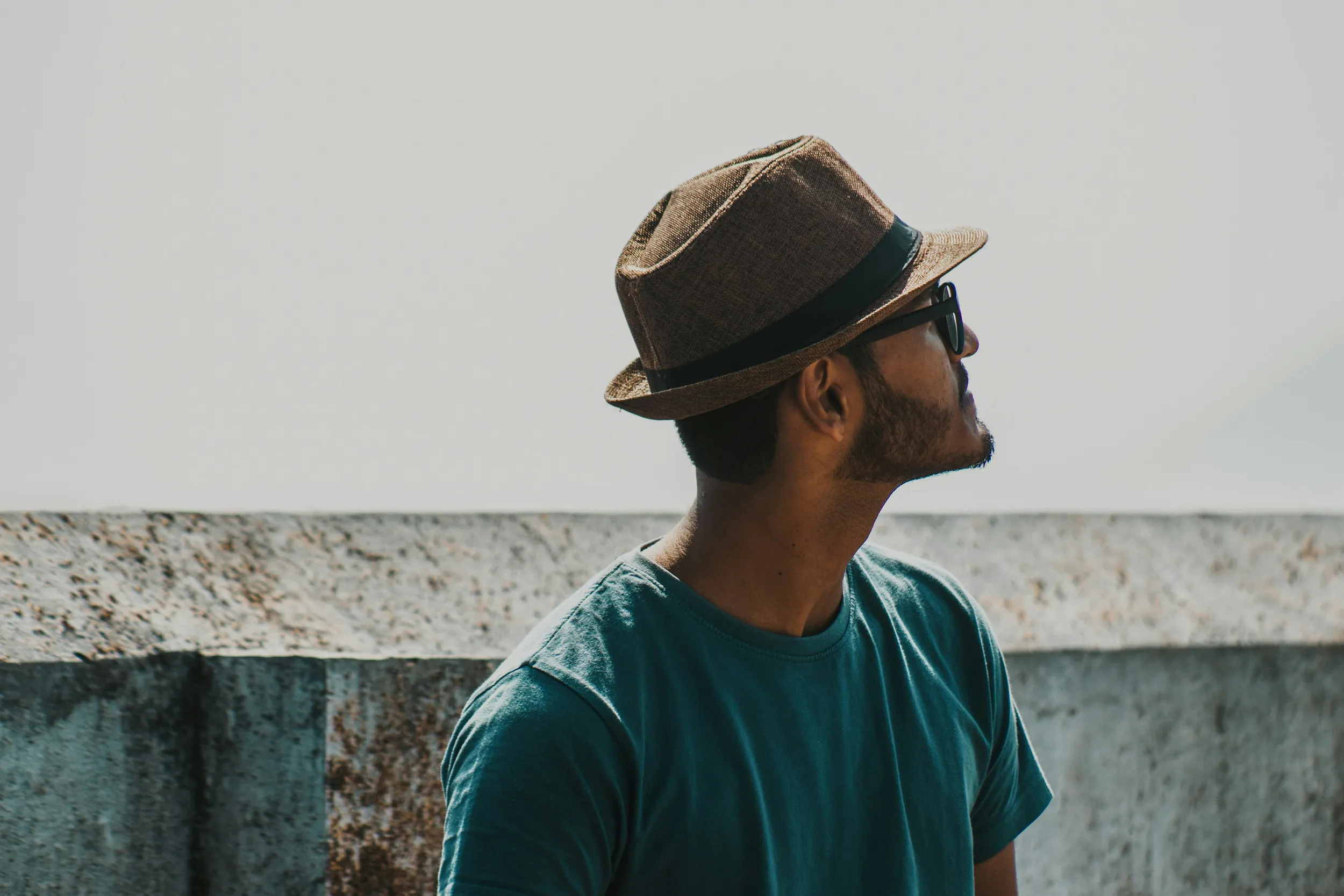 Stylish man wearing hat and sunglasses outdoors, casual fashion portrait