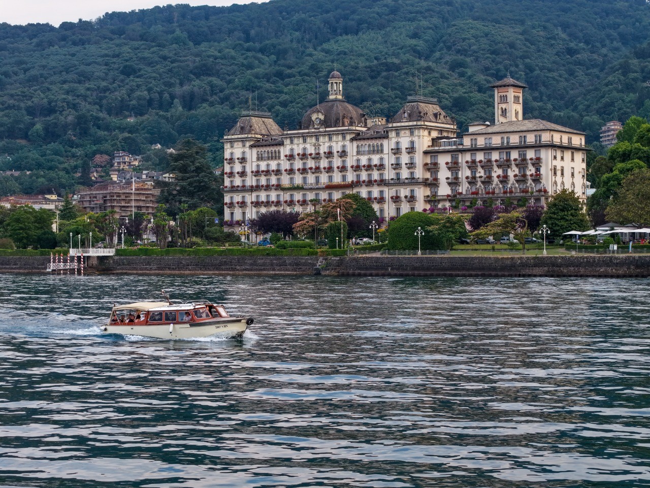 Grand hôtel au bord d’un lac et bateau-taxi sur l’eau, road trip Italie