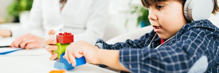 A child engaged in a playful activity, focusing on a colorful toy while an adult assists nearby.