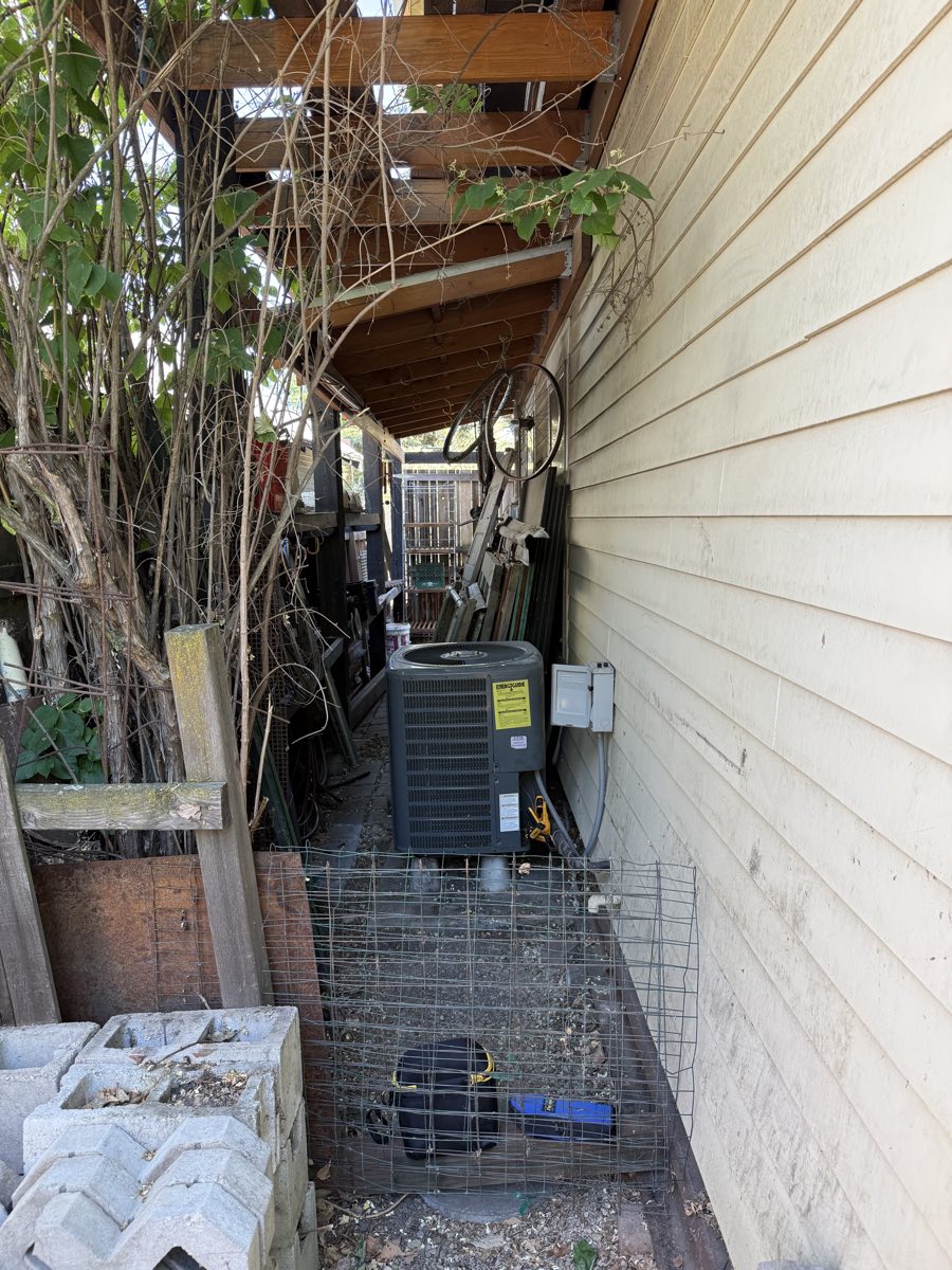 A air conditioner condenser under a deck at a home.