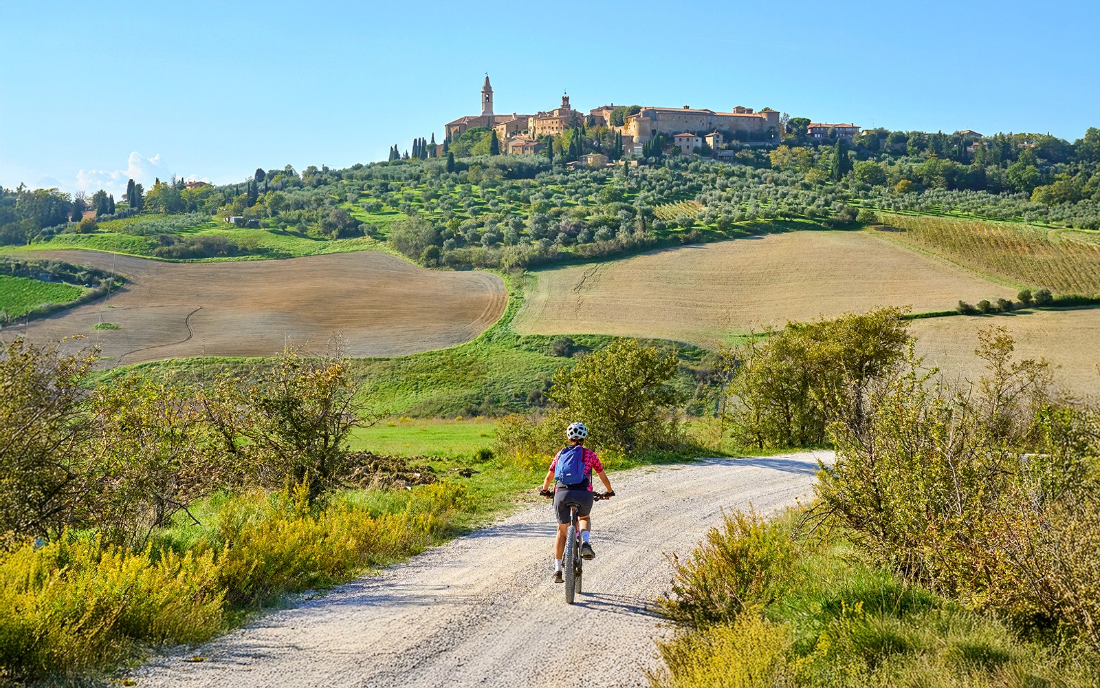 Rowerzyści jeżdżący na rowerach elektrycznych przez malowniczą toskańską wieś z falującymi wzgórzami i winnicami.