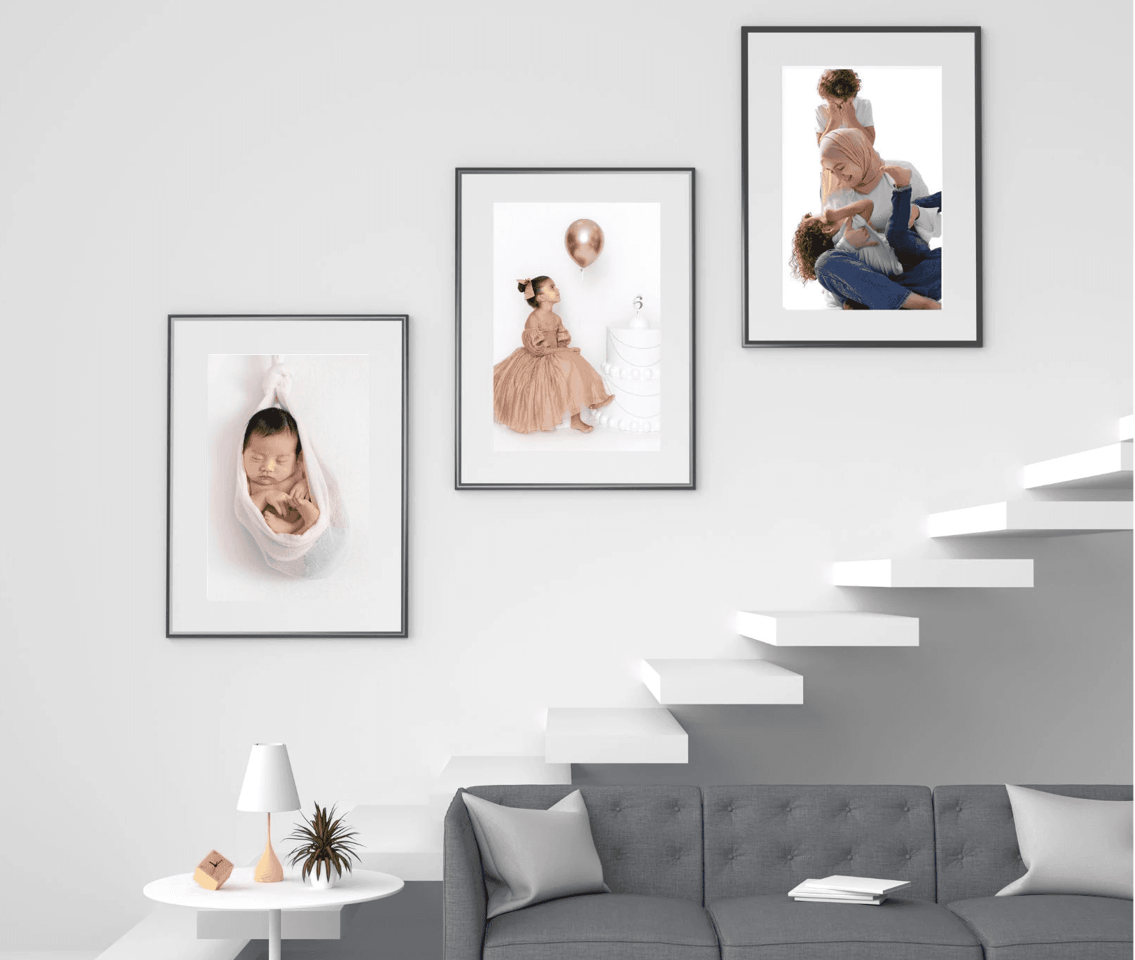 Gallery wall mockup with three black-framed family portraits above a gray sofa and white staircase.