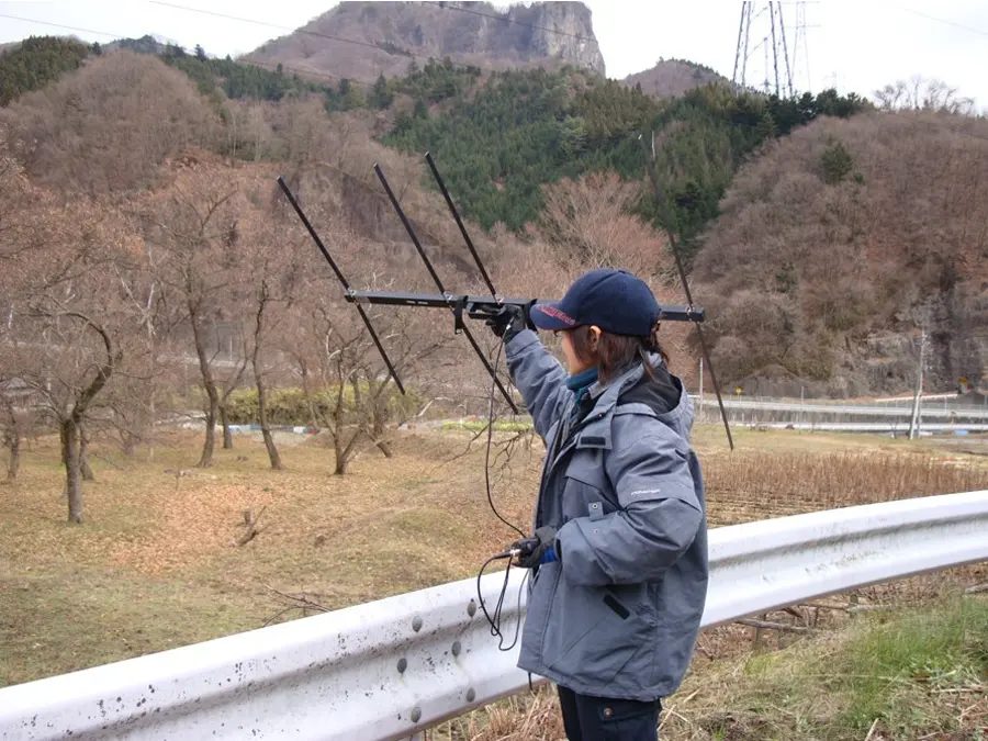 アンテナを持って電波を探す調査員