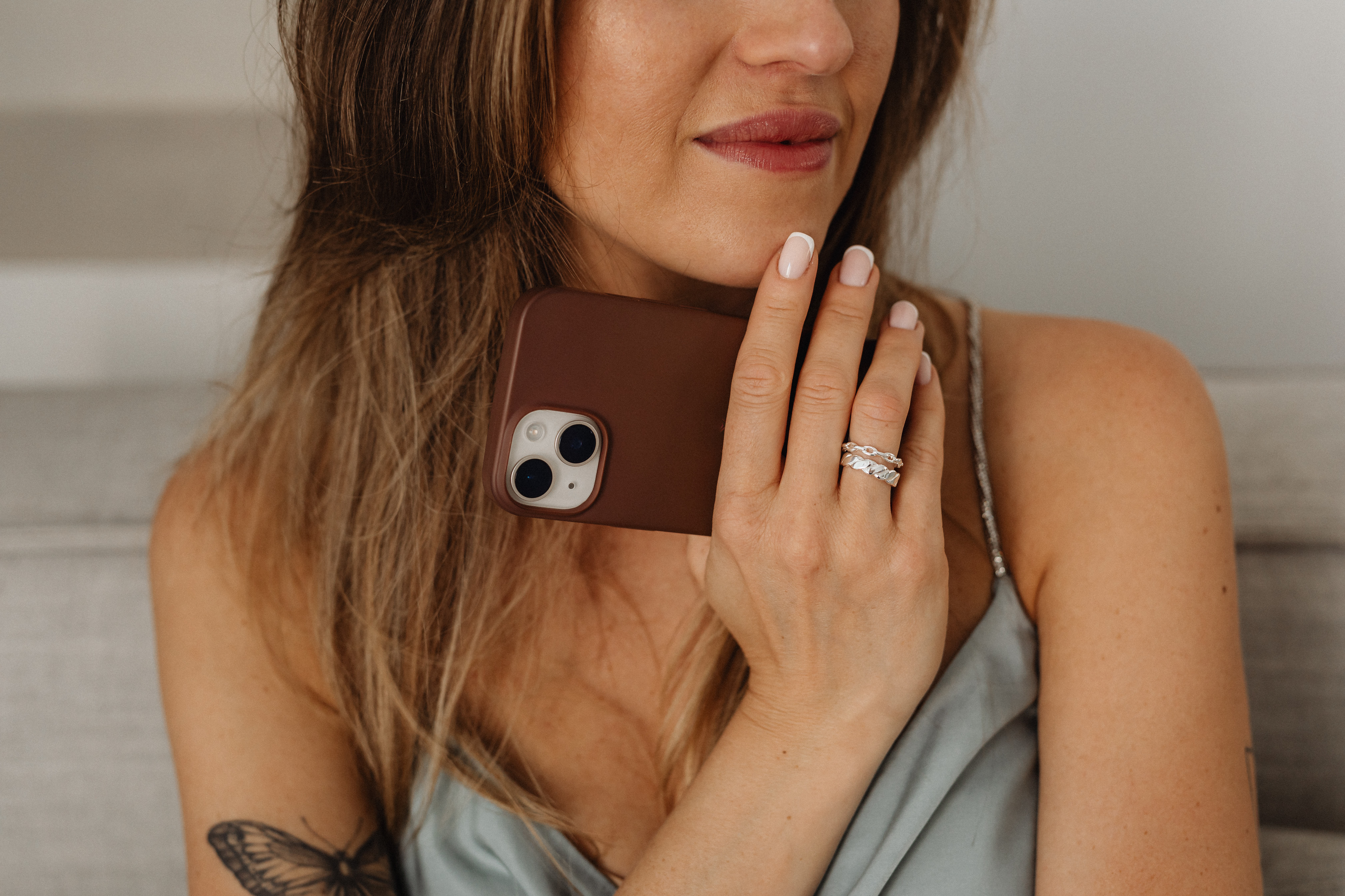 Close-up of a woman holding a smartphone near her face, showing her hand and ring.