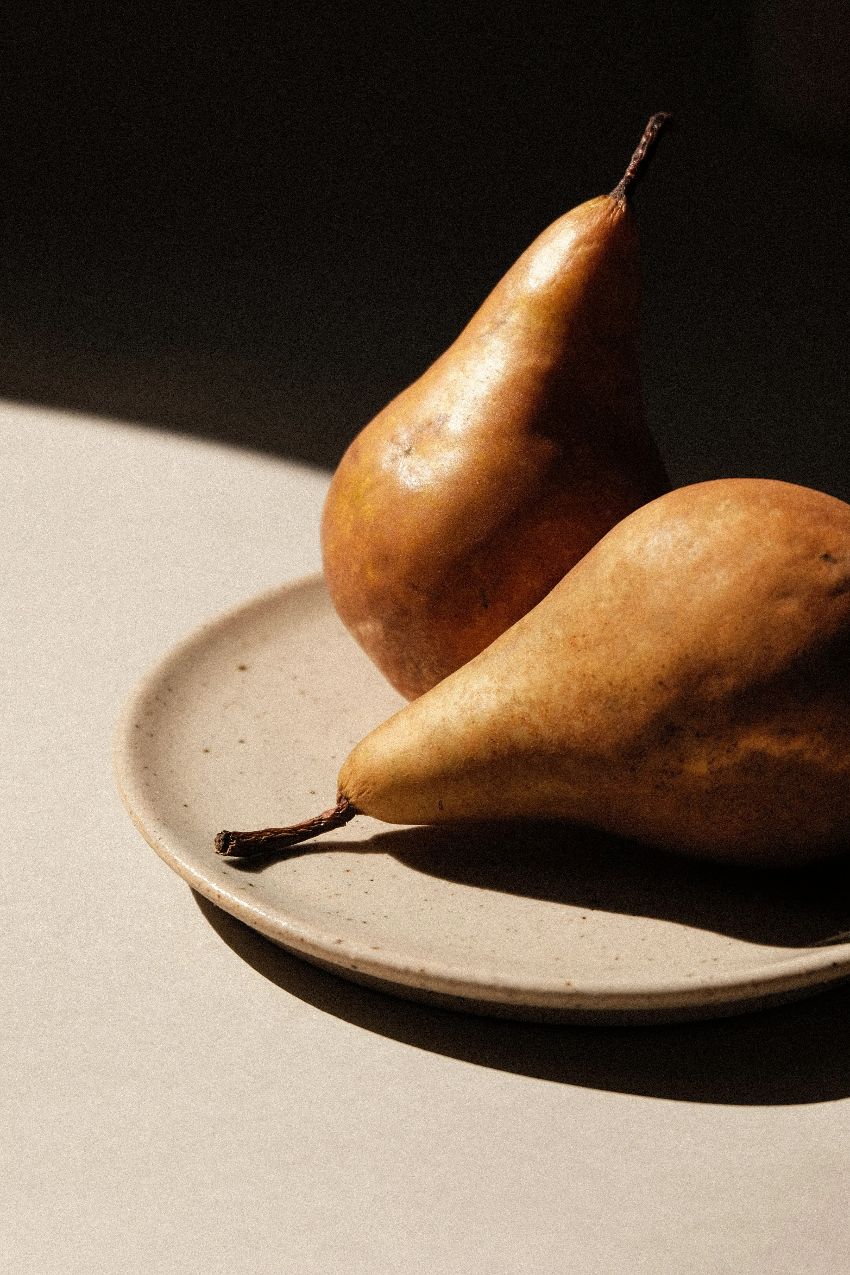 A scene of a ceramic plate with two pears on it