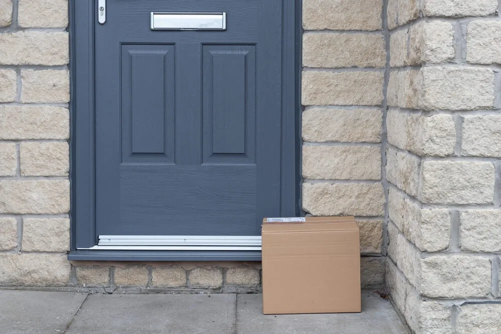 Cardboard package left on a doorstep by a blue door.
