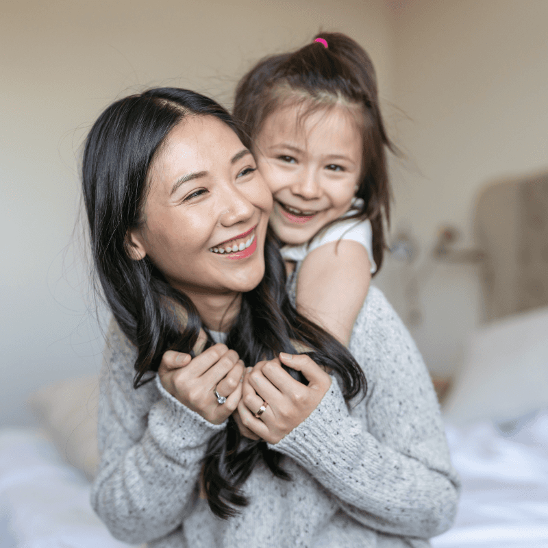 Smiling female teacher in glasses with arms crossed in a bright, colorful classroom