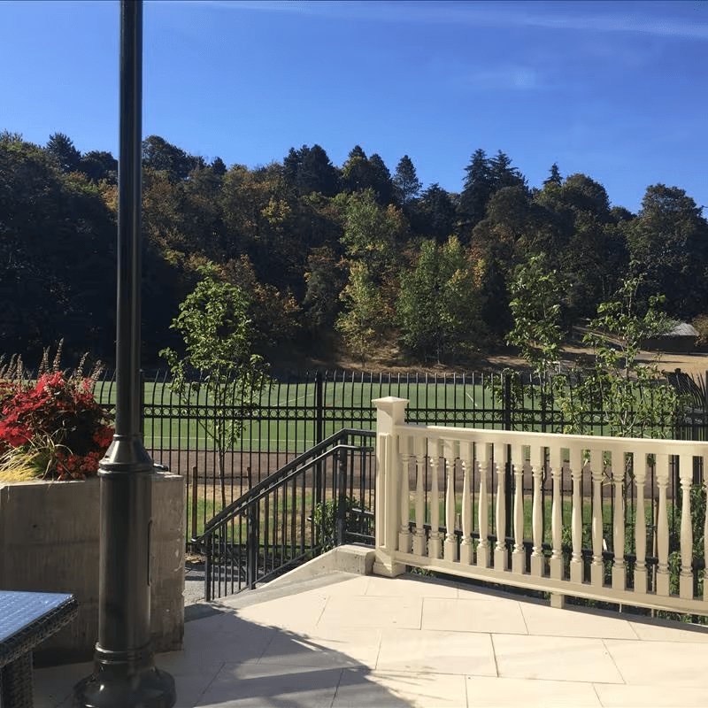 Assisted living community with memory care featuring outdoor seating and views of nearby soccer fields for residents to enjoy watching games.